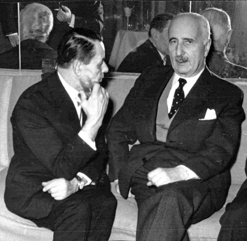 Fotografia ukazuje dwóch mężczyzn. Po lewej siedzi tyłem do widza  Armand Vetulani. Ubrany jest w garnitur i białą koszulę. Jest zwrócony w stronę mężczyzny po prawej. Jest to Władysław Tatarkiewicz. Siedzi on na krześle i skierowany jest w kierunku oglądającego. Ma na sobie garnitur, białą koszulę i krawat. Za mężczyznami znajduje się lustro, w którym odbijają się postacie. 