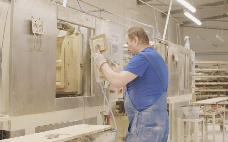 Krok drugi. Wyjmowanie wyrobów z maszyny ceramicznej. Trzecie zdjęcie przedstawia mężczyznę wyjmującego gotowe wyroby za pomocą specjalnej chwytarki.