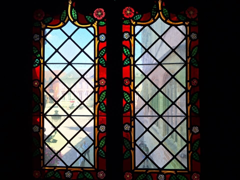 Ilustracja przedstawia fotografię dwóch okien. W kadrze znajdują się jednakowe okna na czarnym tle. Są obramowane barwną dekoracją o takich samych wzorach i kolorystyce.