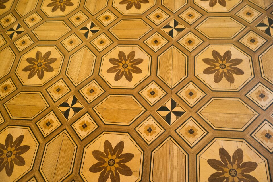 Na ilustracji przedstawiono parkiet w ośmiokąty i kwadraty wypełnione wzorami kwiatów.