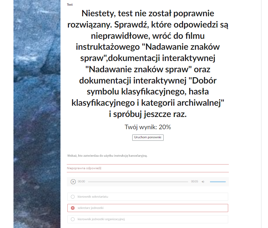 Grafika przedstawia fragment okna z podsumowaniem testu samosprawdzającego. Po prawej stronie jest grafika ozdobna. Obok tekst: “Test. Niestety, test nie został poprawnie rozwiązany. Sprawdź, które odpowiedzi są nieprawidłowe, wróć do filmu instruktażowego "Nadawanie znaków spraw", dokumentacji interaktywnej "Nadawanie znaków spraw" oraz dokumentacji interaktywnej "Dobór symbolu klasyfikacyjnego, hasła klasyfikacyjnego i kategorii archiwalnej" i spróbuj jeszcze raz. Twój wynik: dwadzieścia procent”. Poniżej jest przycisk w formie prostokątnej ramki z napisem: “Uruchom ponownie”, który służy do ponownego uruchomienia testu. Pod przyciskiem znajduje się jedno z rozwiązanych zadań. Polecenie: “Wskaż, kto zatwierdza do użytku instrukcję kancelaryjną”. Pod poleceniem treść informacji zwrotnej: “Niepoprawna odpowiedź”. Pod informacją zwrotną trzy prostokątne ramki z odpowiedziami. Pierwsza: “kierownik sekretariatu”. Druga, zaznaczona na czerwono ramka: “sekretarz jednostki”. Trzecia: “kierownik jednostki organizacyjnej”.
