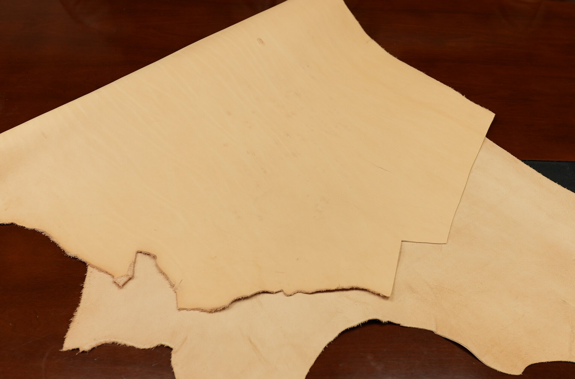 Zdjęcie przedstawia płat skóry garbowanej roślinnie. Od strony lica i mizdry skóra jest beżowa. 
