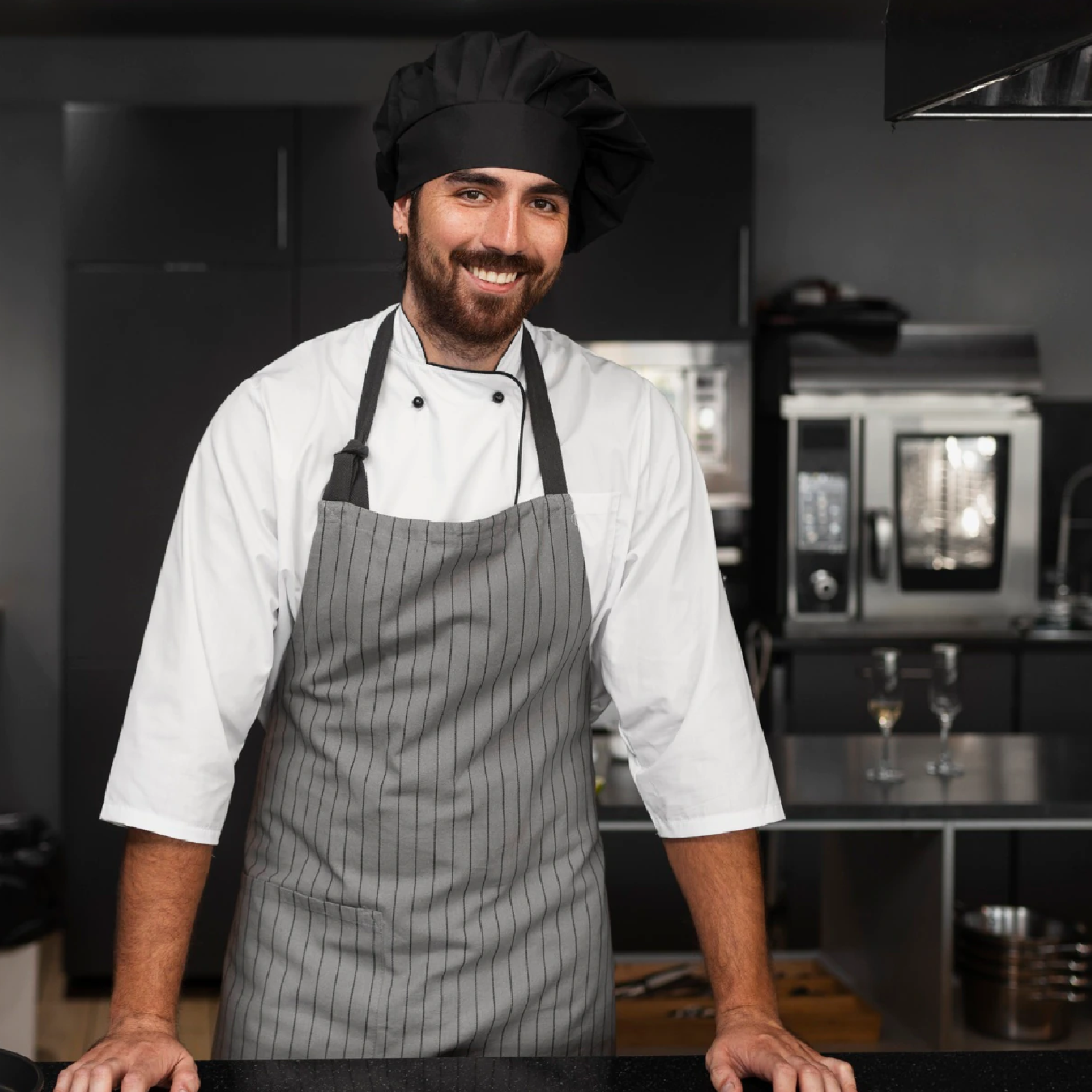 Zdjęcie przedstawia młodego mężczyznę ubranego w fartuch oraz czapkę kucharską. 