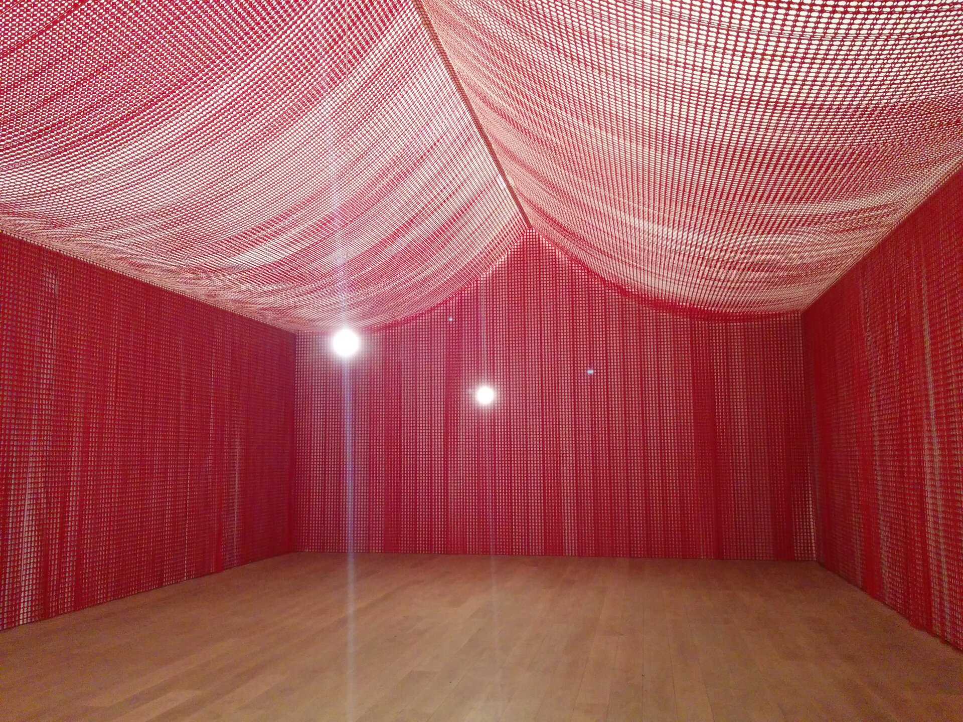 Zdjęcie przedstawia instalację artystyczną zatytułowaną „Pokój wojenny” i wykonano je we wnętrzu instalacji. Jako odbiorcę otaczają nas trzy ściany na planie prostokąta wykonane z czerwonych podziurkowanych karteczek, dzięki czemu wpada przez nie światło. Dach tworzą te same karteczki, umocnione prostą linią wzdłuż dłuższej ściany i uginające się z dwóch stron niczym baldachim. Poprzez wpadające światło, dach wydaje się jaśniejszy od ścian. Na ścianie przed odbiorcą dzieła rozbłyskują dwa światła lamp. Podłogę tworzą drewniane panele.