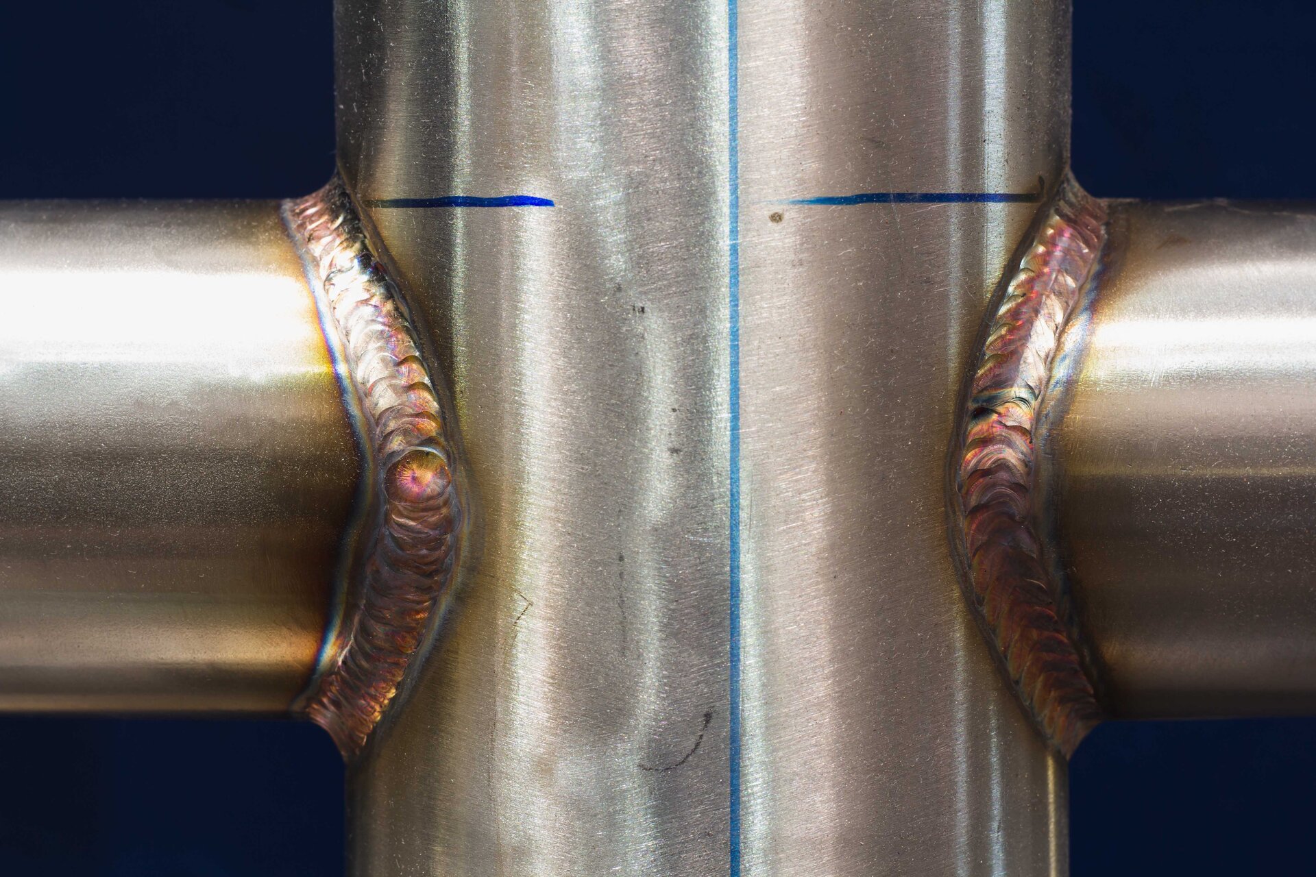 Zdjęcie przedstawia stalowe rury połączone krzyżowo przez spawanie. W miejscu łączenia widoczne jest zgrubienie.