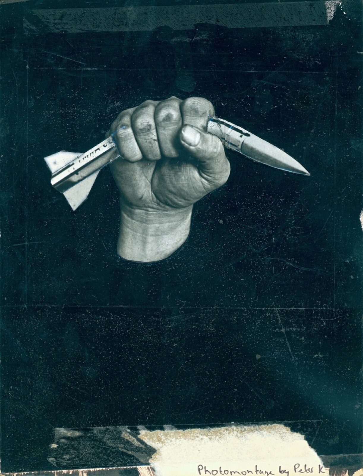 Ilustracja przedstawia ciemne, czarno‑turkusowe tło, na którym znajduje się ludzka dłoń zgniatająca w pół pocisk balistyczny. Tło jest porysowane, z widocznymi wytartymi fragmentami. Dłoń, ukazana pośrodku obrazu, jest jasna, ale na skórze oraz pod widocznym paznokciem kciuka można zauważyć zabrudzenia. Pocisk, dwukrotnie dłuższy od dłoni, zgina się pod jej naporem. 