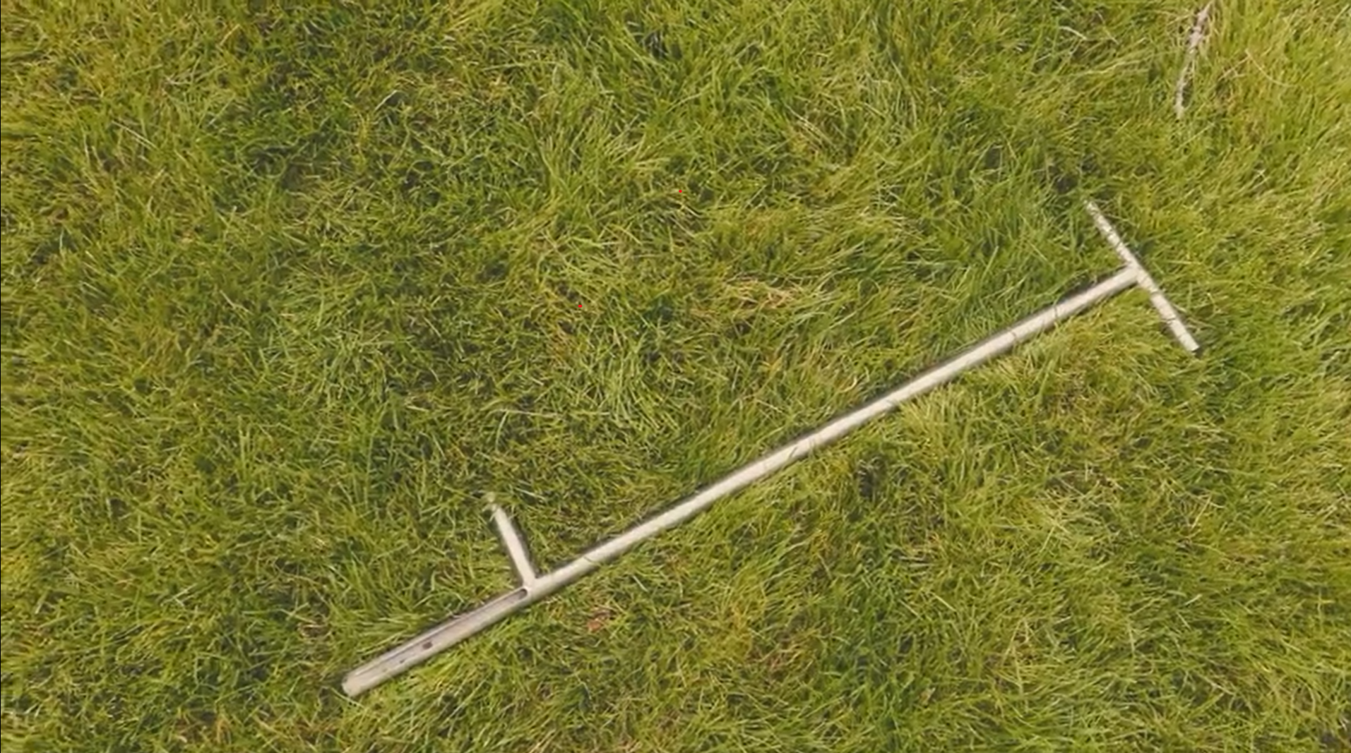 Zdjęcie przedstawia laskę Egnera. To długi, metalowy pręt z większym prostopadłym uchwytem na górze oraz mniejszym w dolnej części. 