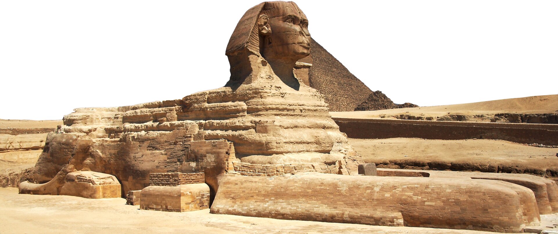 Na zdjęciu widać sfinksa - mityczne stworzenie, przedstawiane jako lew z ludzką głową. Za nim jest stożkowa budowla, czyli piramida.