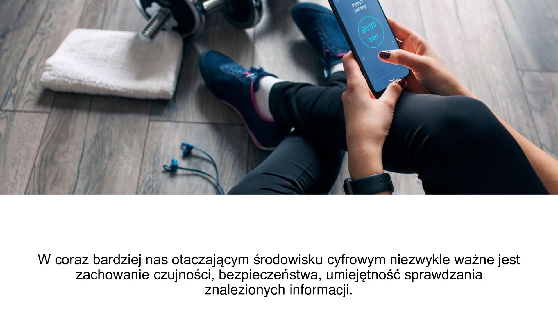 Biały slajd. W górnej części zdjęcie przedstawiające nogi damskie w leginsach sportowych. Kobieta trzyma w dłoniach, opartych o nogę, telefon, na którym pojawia się minutnik. Przy nogach słuchawki, biały ręcznik i hantla. U dołu slajdu tekst: „W coraz bardziej nas otaczającym środowisku cyfrowym niezwykle ważne jest zachowanie czujności, bezpieczeństwa, umiejętność sprawdzania znalezionych informacji”.