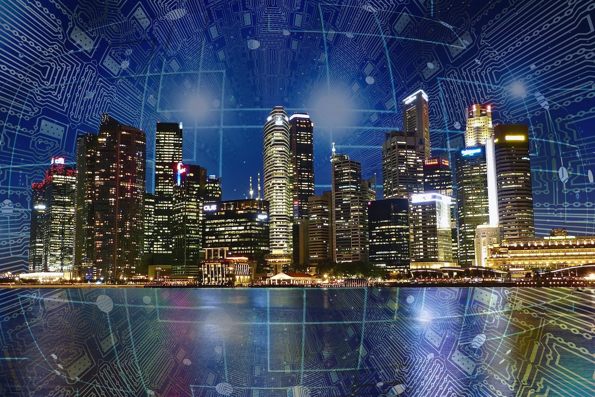 Ilustracja przedstawia panoramę dużego miasta. Znajdują sie tu liczne, stojące obok siebie drapacze chmur. W budynkach włączone jest światło.