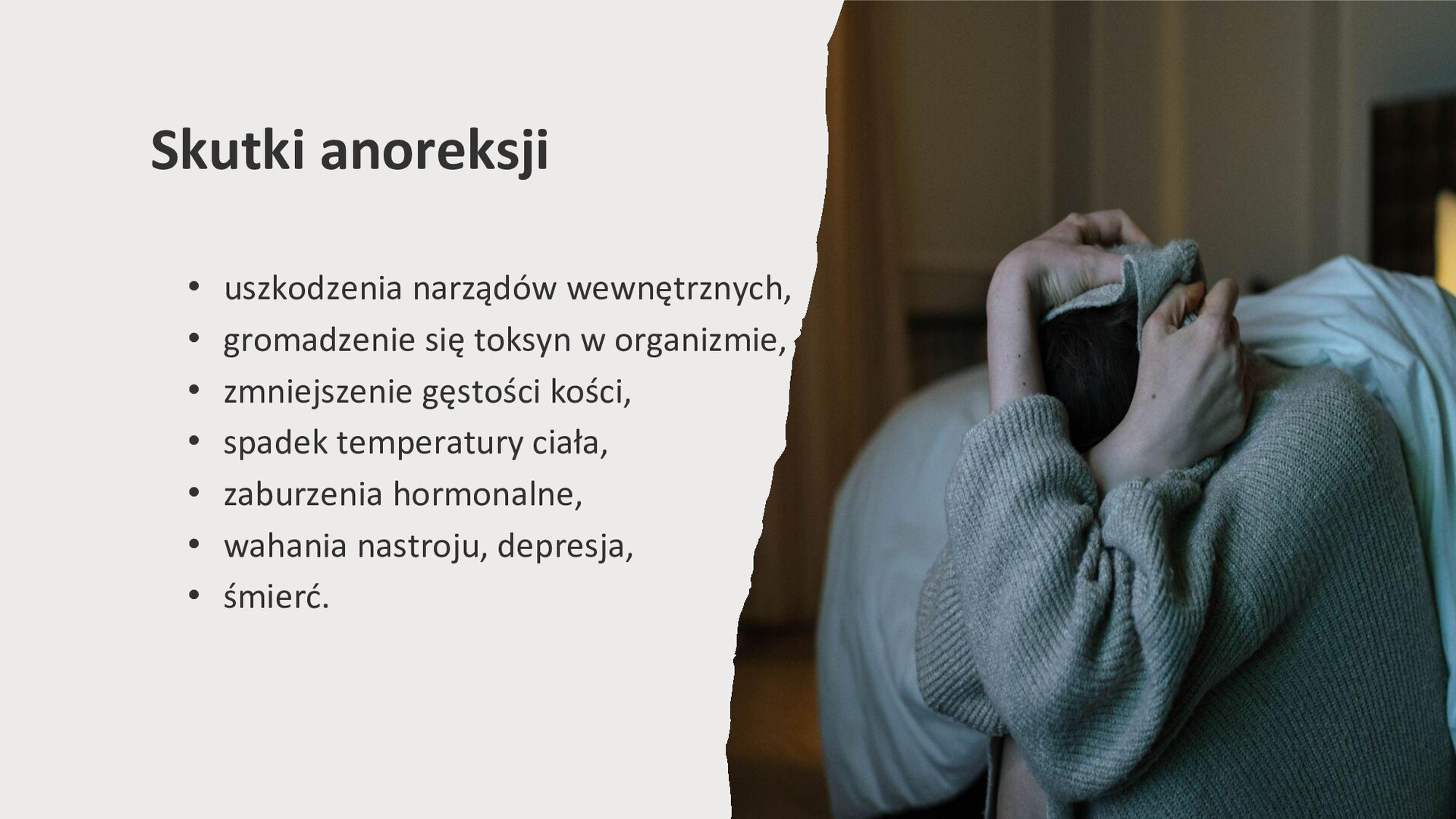 Jasnoszary slajd. Z prawej strony slajdu skulona kobieta, która ukrywa głowę w swetrze i obejmuje ją dłońmi. Z lewej strony slajdu tekst: „Skutki anoreksji. Uszkodzenia narządów wewnętrznych. Gromadzenie się toksyn w organizmie. Zmniejszenie gęstości kości. Spadek temperatury ciała. Zaburzenia hormonalne. Wahania nastroju, depresja. Śmierć”.