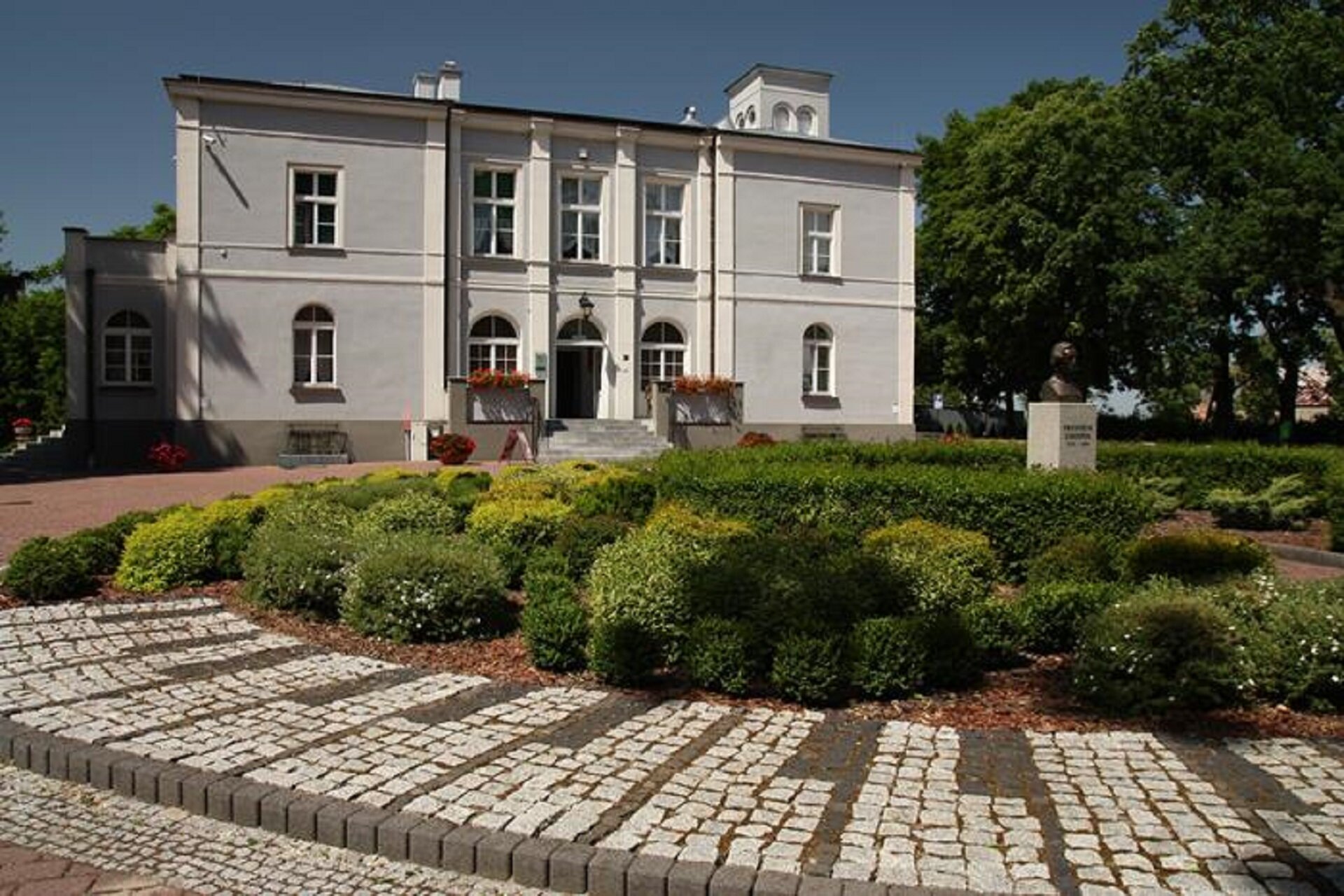 Zdjęcie przedstawia dwór w Szafarni w stylu klasycystycznym. Przed budynkiem znajduje się ogród z zielonymi krzewami. Budynek został wykończony szarym tynkiem. Za nim, w ogrodzie stał drewniany majątek Dziewanowskich, w którym w miesiącach letnich 1824 i 1825 roku przebywał Fryderyk Chopin. W ogrodzie znajduje się pomnik popiersia kompozytora.