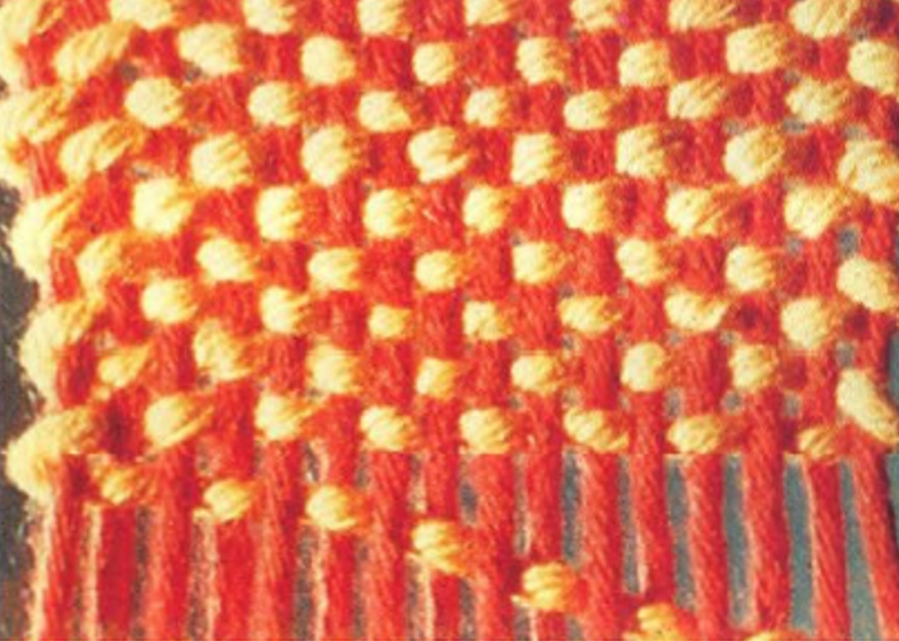 Na zdjęciu widoczny fragment materiału w powiększeniu, w kolorze czerwono‑pomarańczowym.