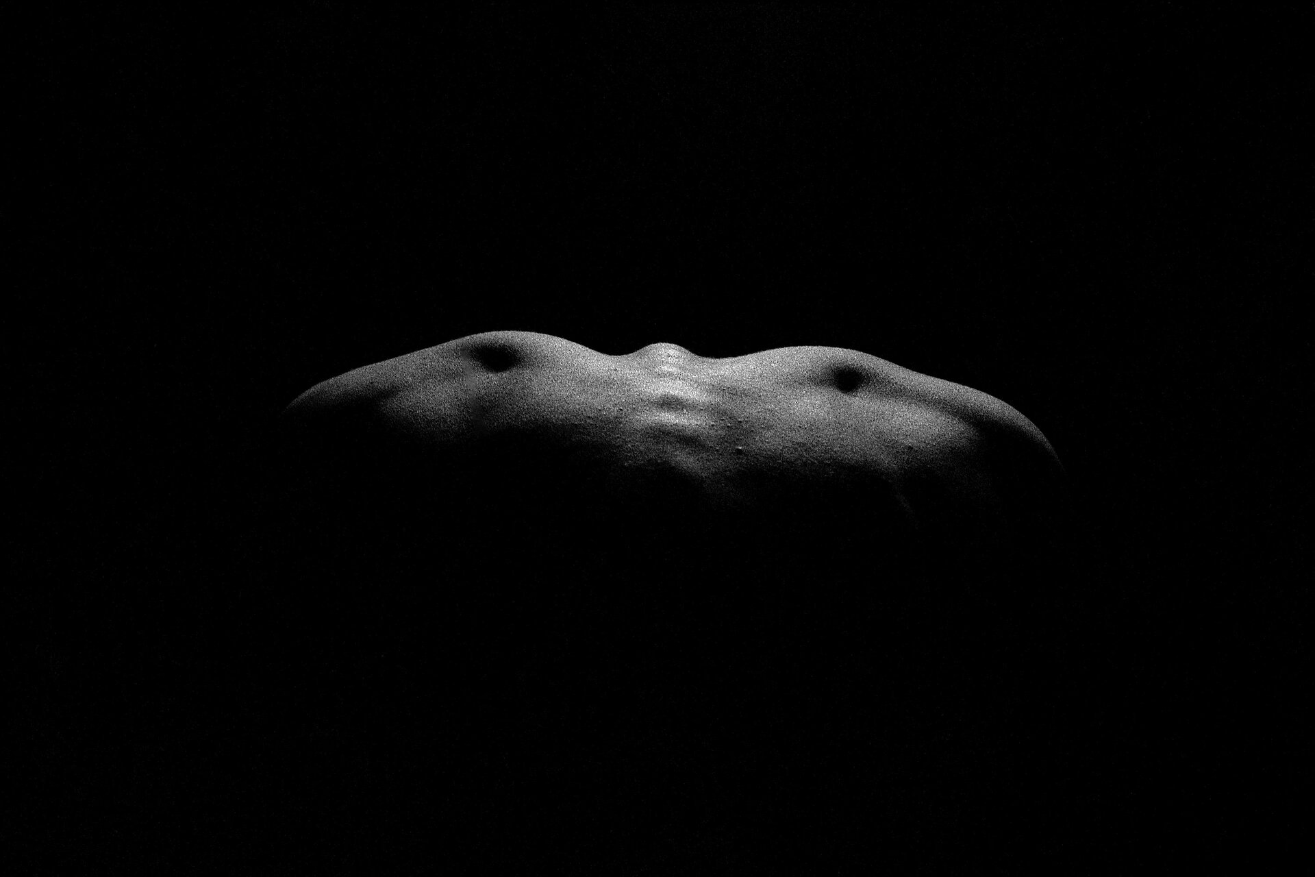 Ilustracja przedstawia fotografię Anny Koli „Ćma”. Ukazuje fragment oświetlonych, ludzkich pleców na czarnym tle z wyeksponowanym kręgosłupem i łopatkami. Układające się na plecach światło wygląda jak ćma.