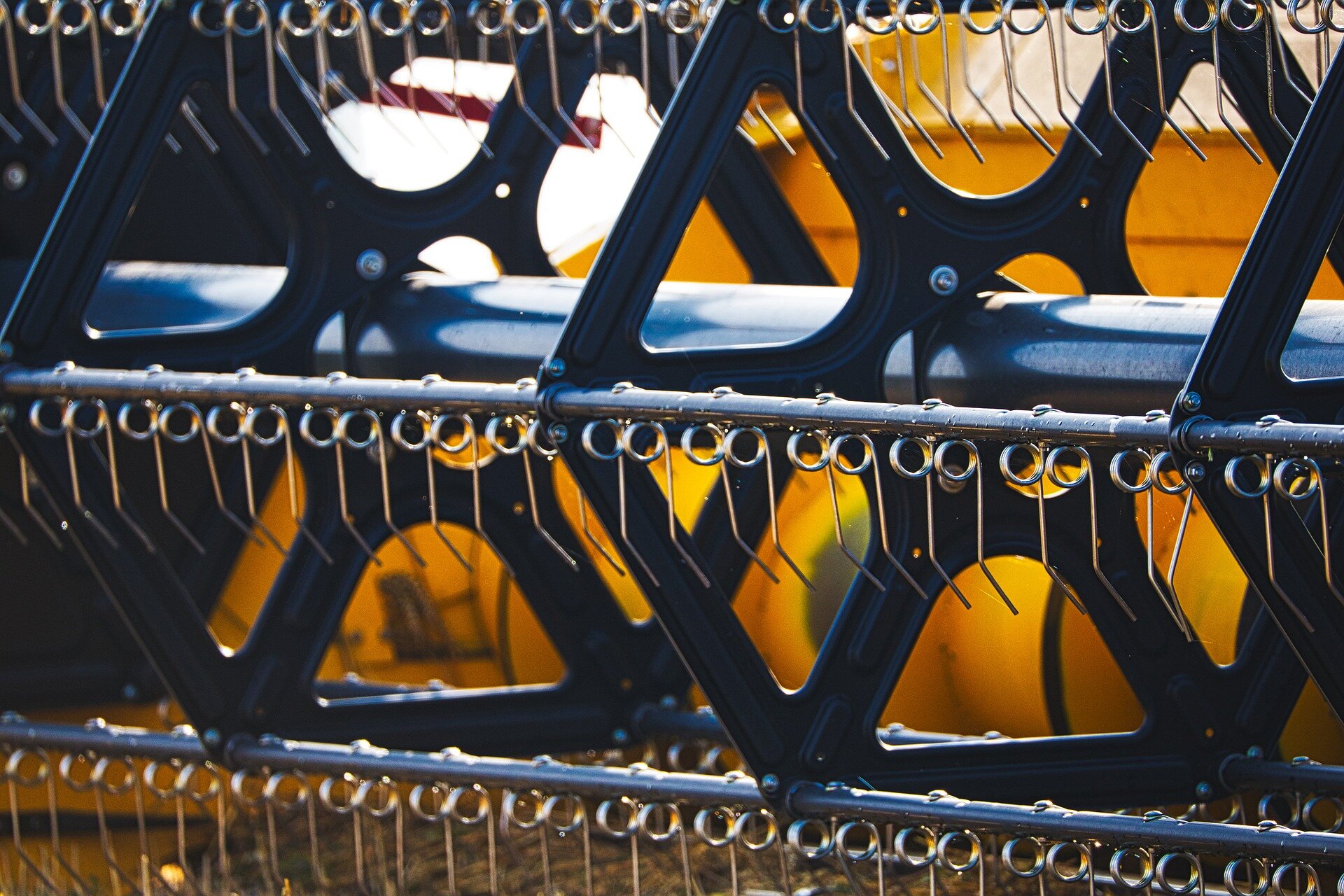 Zdjęcie przedstawia zbliżenie na nagarniacz. Jest to element znajdujący się na przodzie zespołu żniwnego. Nagarniacz ma kształt pięciokąta. Nachyla on zboże w kierunku zespołu tnącego, a także podaje skoszoną masę roślinną na podajnik ślimakowo‑palcowy.