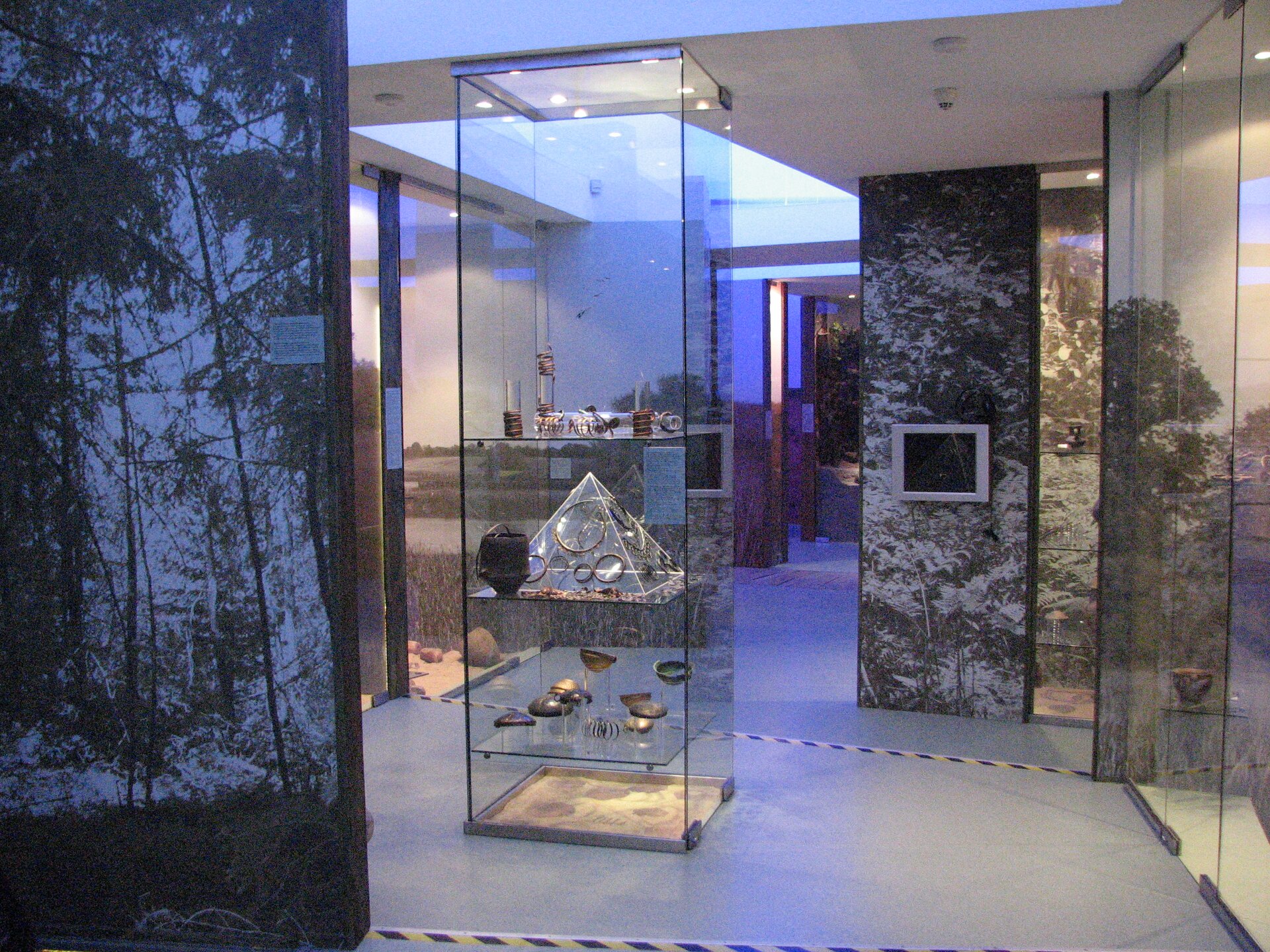 Zdjęcie przedstawiające ekspozycję szklanych naczyń znajdującą się w szklanej gablocie.