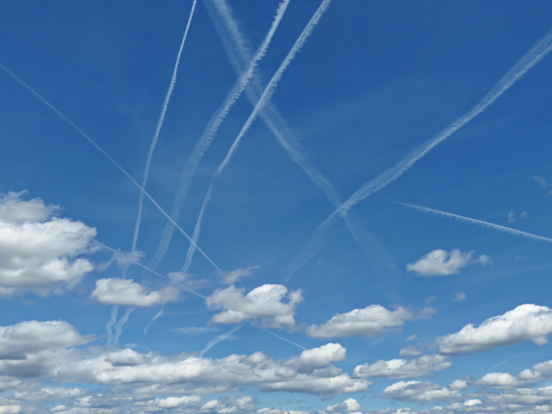 Zdjęcie przedstawia niebieskie niebo z chmurami. Są to pojedyncze chmury kłębiaste oraz chmury w postaci długich linii.