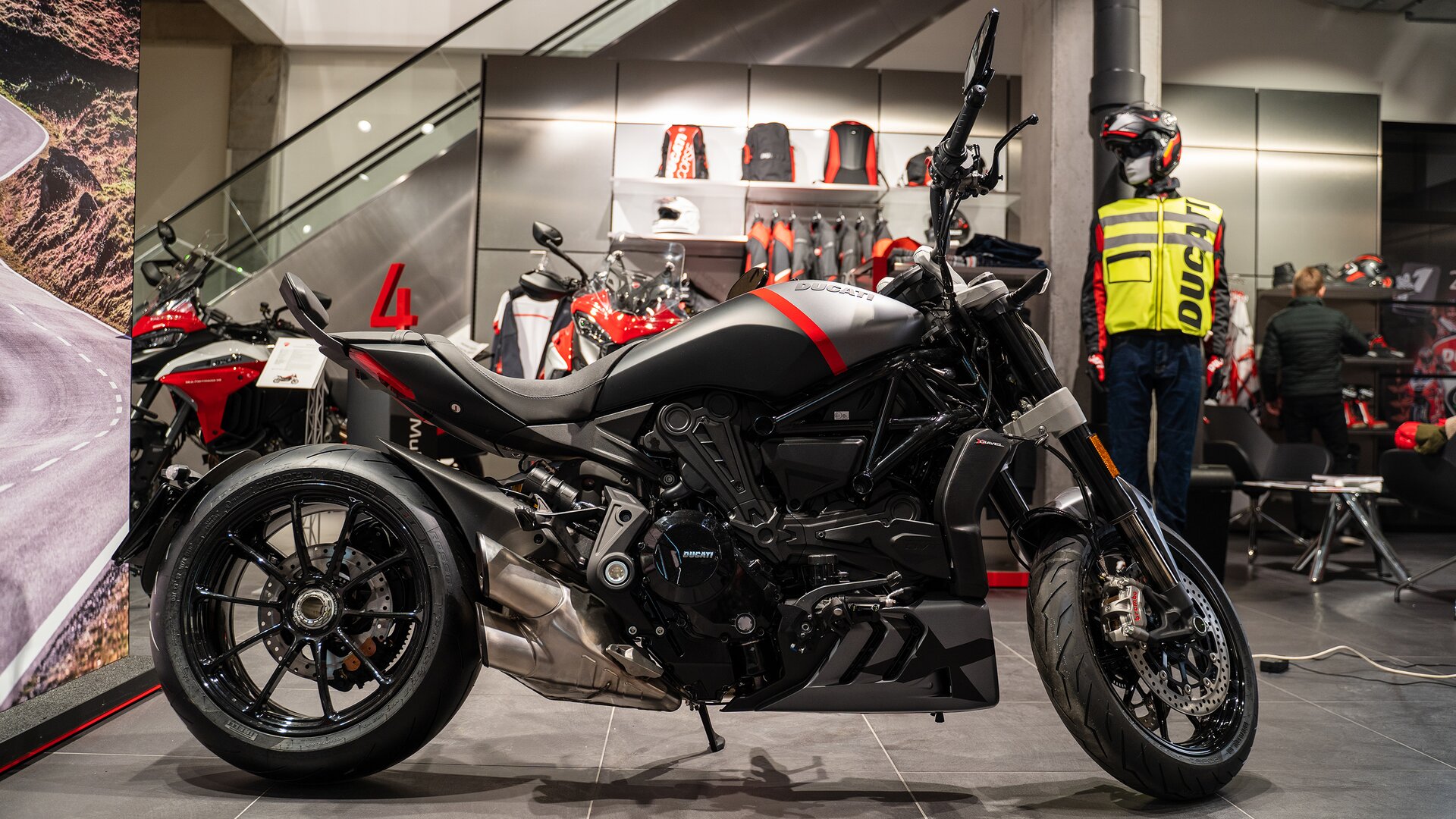 Zdjęcie przedstawia motocykl. Nie posiada przedniej szyby. Nie ma osłon aerodynamicznych. Siedzenie oraz bak silnik są w kolorach srebrno‑czarno‑czerwonym. 