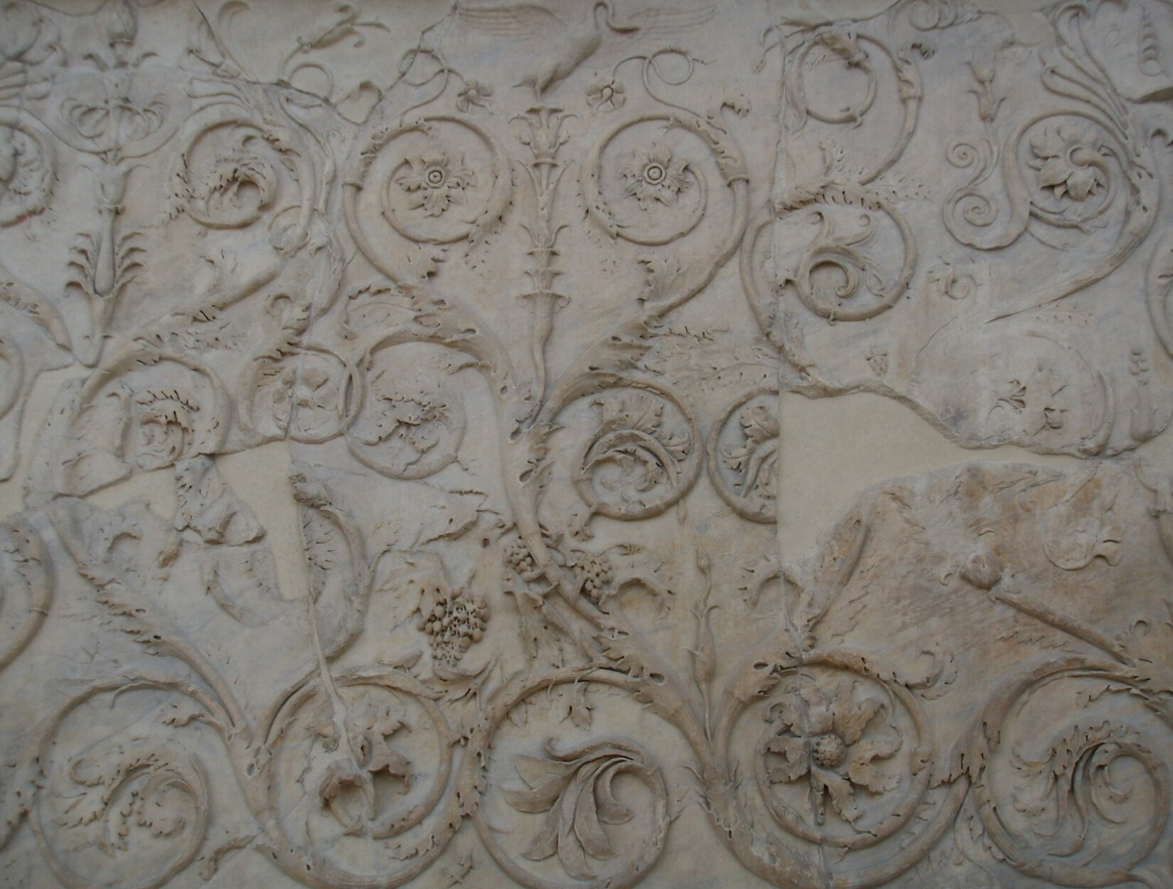 Fotografia przedstawia przykład arabeski - ornamentów roślinnych, które wiją się na szerokości całej ściany. Na końcach zwiniętych gałęzi są różnego rodzaju kwiaty oraz liście.