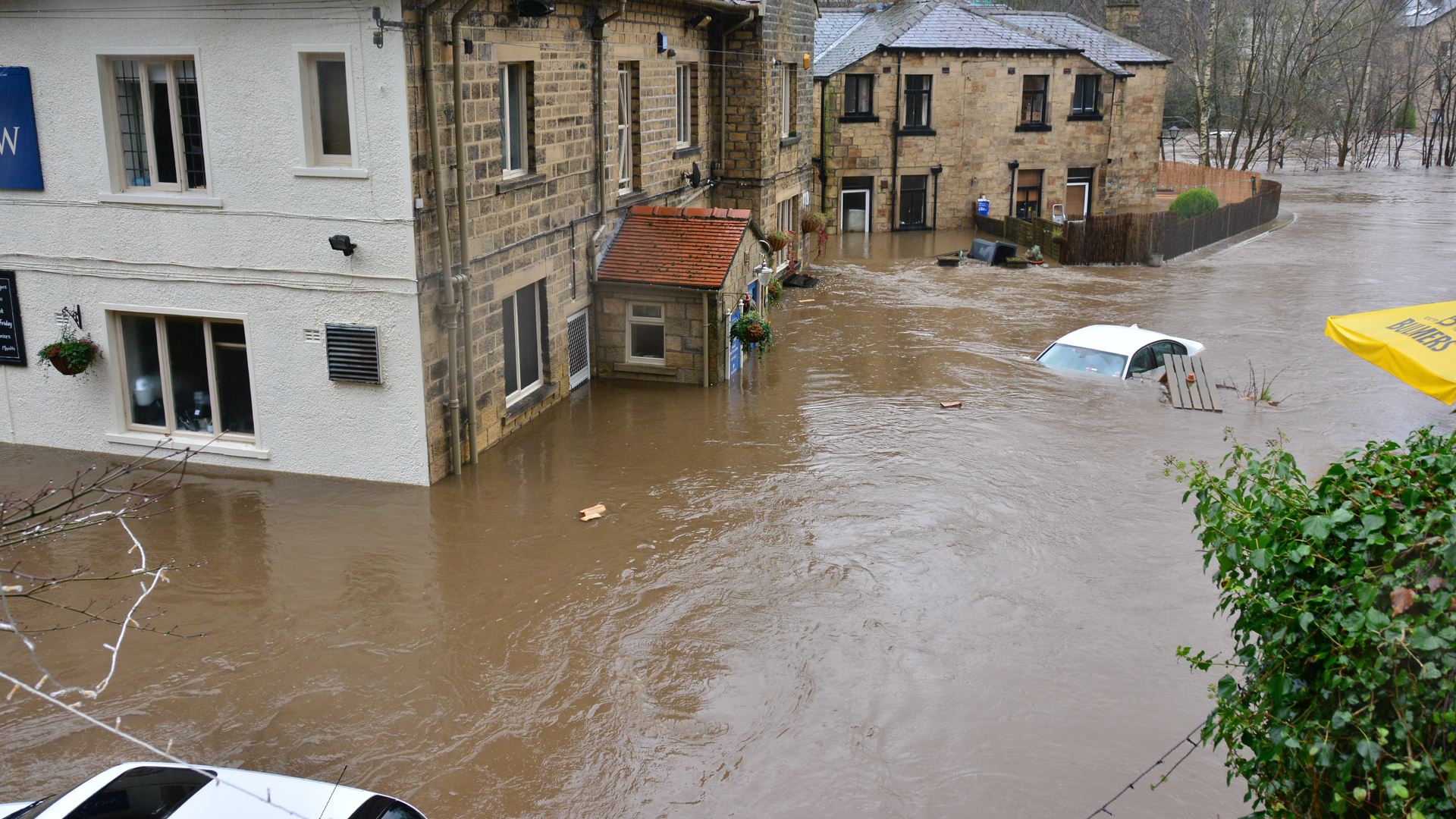 Zdjęcie przedstawia zalane domy i samochody w czasie powodzi.
