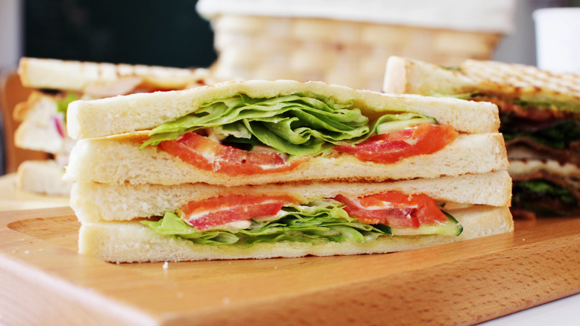 Zdjęcie przedstawia trójkątne włoskie kanapki z białego pieczywa przełożone dodatkami, między innymi sałatą.