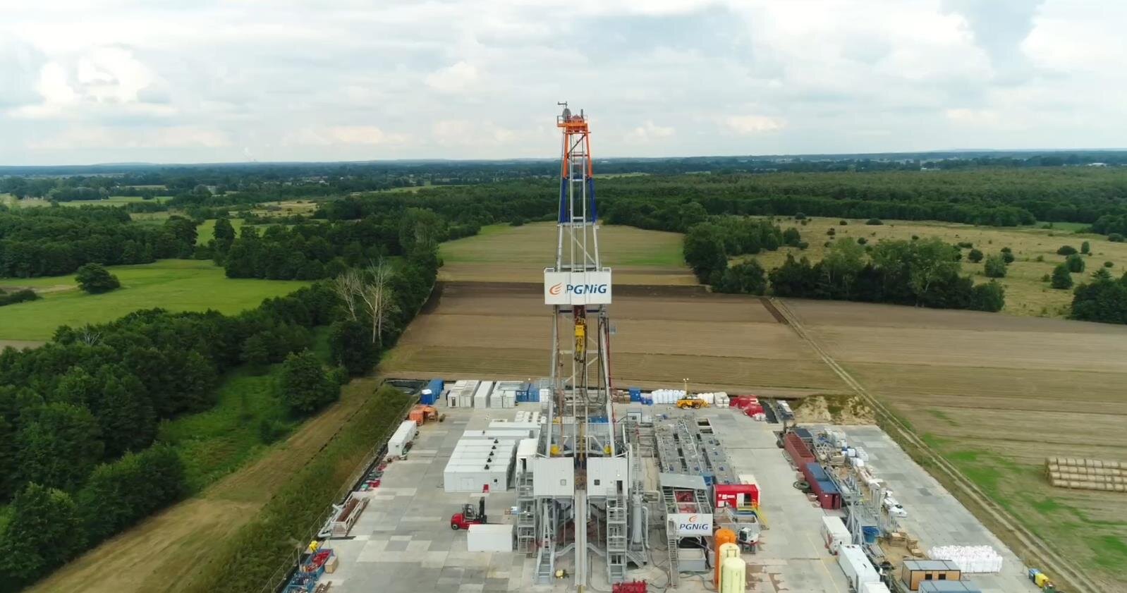 Na zdjęciu widoczny jest wieżomaszt wraz z placem widoczny z lotu ptakaPlac wiertniczy widoczny jest z lotu ptaka. Ma kształt prostokąta. Podstawa placu jest wyłożona betonowymi płytami. W centralnym punkcie placu znajduje się wieżomaszt. Wieżomaszt jest w kształcie litery A. Wieżomaszt ma dwa galerie. Na dolnej większej galerii znajduje się podbudówka. Podbudówka wykonana jest z blachy falistej. Na górnej podbudówce widać napis: PGNiG. Na szczycie wieżomasztu zamontowany jest element o kształćie walca. Jest to wielobroczek górny.Wieżomasz znajduje się pomiędzy małymi obiektami przypominającymi kontenery.W tle zdjęcia widać tereny leśne.