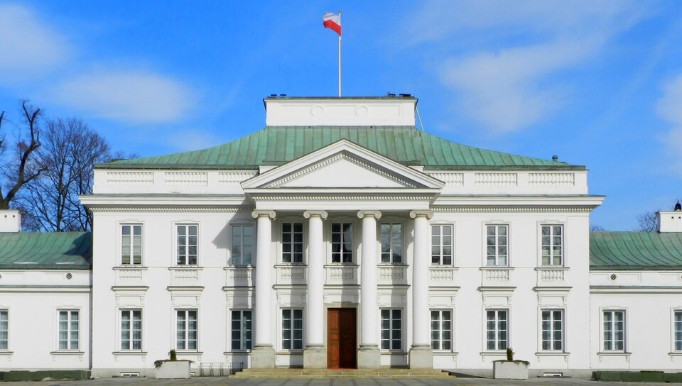 Na fotografii klasycystyczny pałac. Wejście do pałacu jest poprzez kolumnowy portyk w porządku jońskim, zakończony tympanonem. Budynek jest jednopiętrowy. Okna w pałacu są wysokie. Na dachu budynku znajduje się maszt, na którym powiewa biało‑czerwona flaga. Budynek jest zarządzany przez Kancelarię Prezydenta RP.