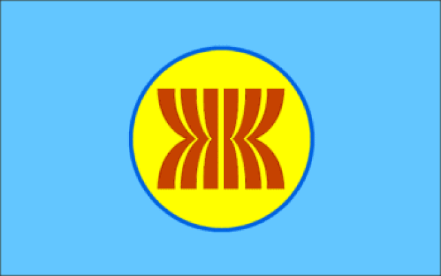 Ilustracja przedstawia niebieską flagę. Na środku znajduje się czerwone kółko z białą obwódką. W jego centralnej części znajduje emblemat z żółtych pasów, które po środku są ściśnięte od lewej i prawej.