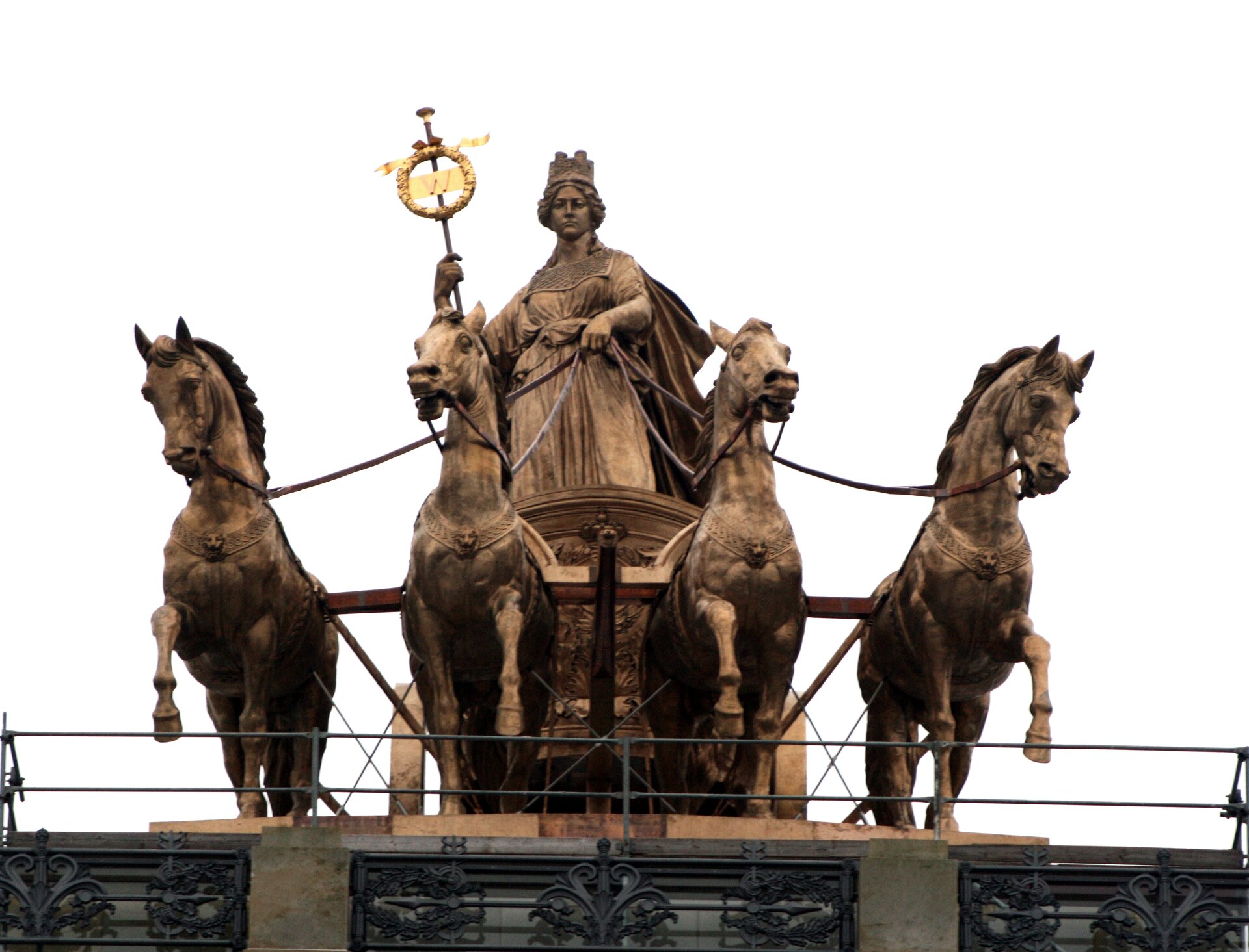 Ilustracja przedstawia rzeźbę Kwadrygi. Rzeźba przedstawia scenę w której cztery zaprzegnięte konie ciągną powóz na którym znajduje się kobieta. Jedną ręką trzyma lejce, drugą przedmiot ze złotym znakiem w kółku.