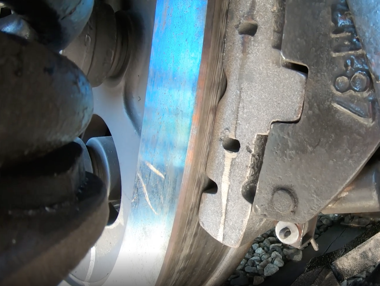 Zdjęcie przedstawia zbliżenie hamulca klockowego. Do krawędzi koła dociśnięty jest klocek hamulca.