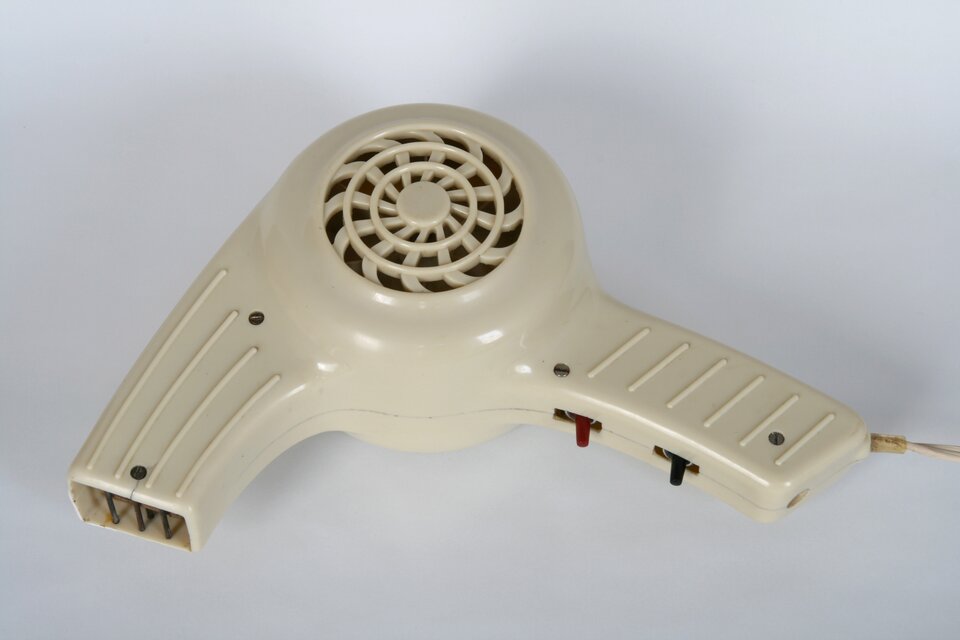 Zdjęcie przedstawia stary model suszarki do włosów. Ma kolor biały.