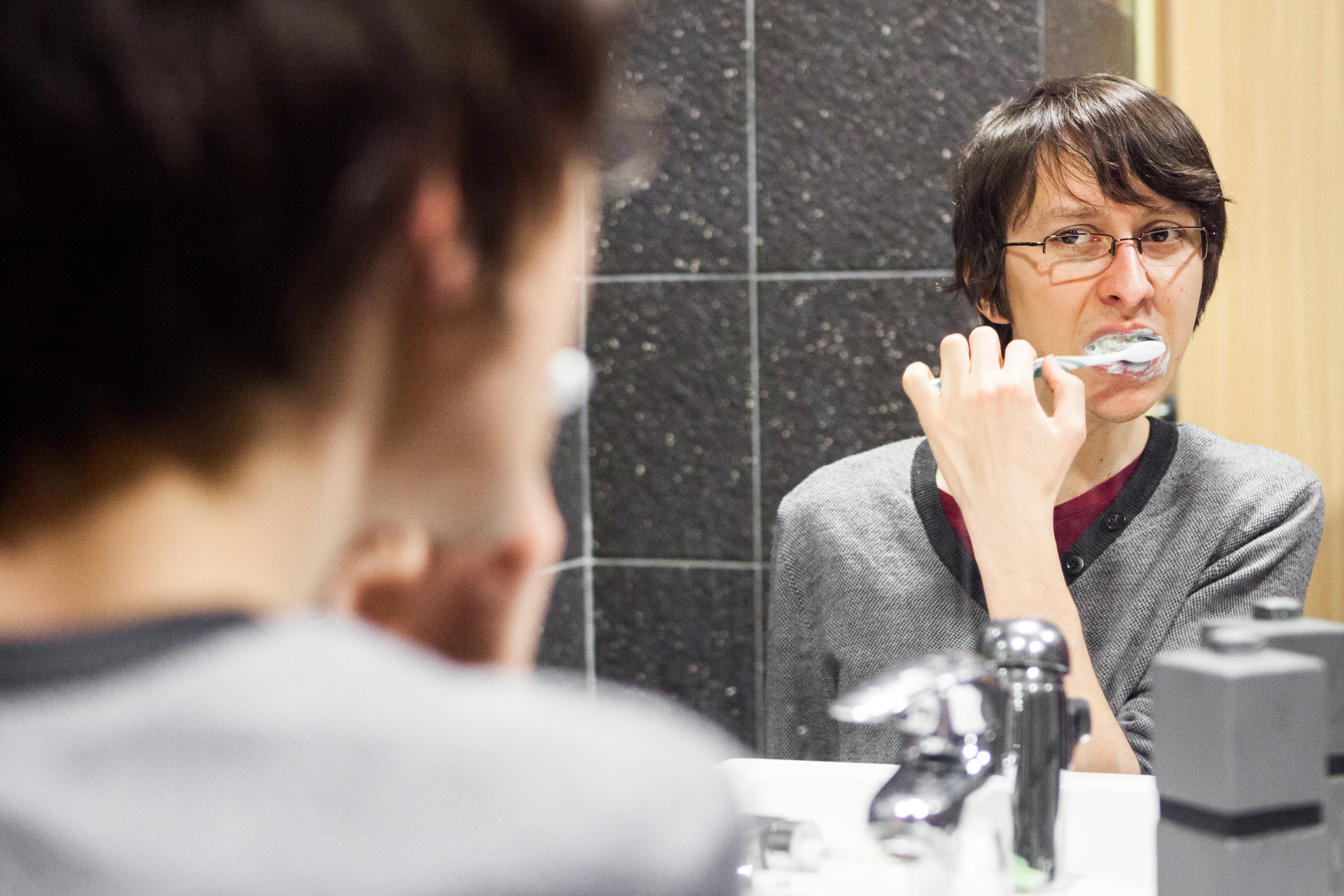 Zdjęcie przedstawiające młodego człowieka myjącego zęby.