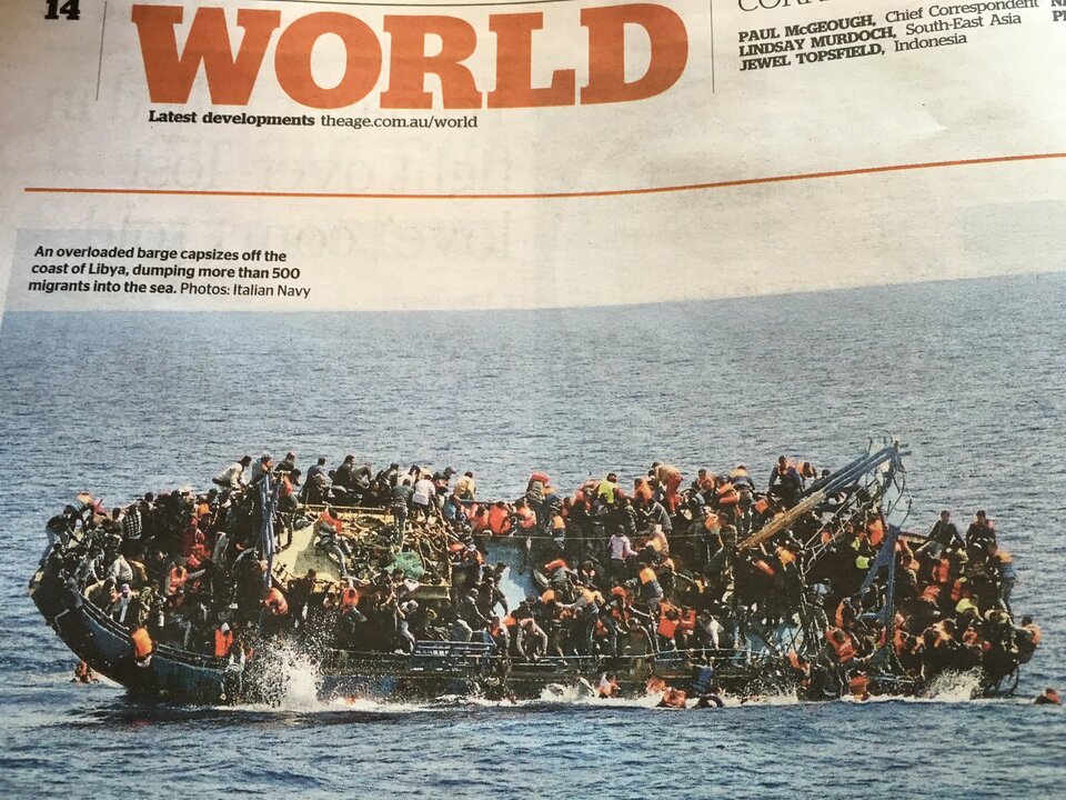 Fotografia przedstawia stronę gazety z artykułem dotyczącym morskiej katastrofy statku z uchodźcami i migrantami. Jednostka pływająca, którą płyną jest przepełniona, jest na niej zbyt dużo osób. Zdjęcie wykonano w momencie, kiedy statek przewraca się na bok i ludzie wpadają do wody.