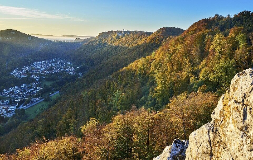 Na fotografii został ujęty Zamek Liechtenstein, który jest położony w miejscowości Maria Enzersdorf w Dolnej Austrii w parku natury Föhrenberge. Zamek stoi na wzgórzu na wysokości około 300 metrów nad poziomem morza. Na zdjęciu po prawej stronie ciągnie się grzbiet górski, na którym stoi zamek. U jego podnóża rozciąga się z kolei miejscowość. 