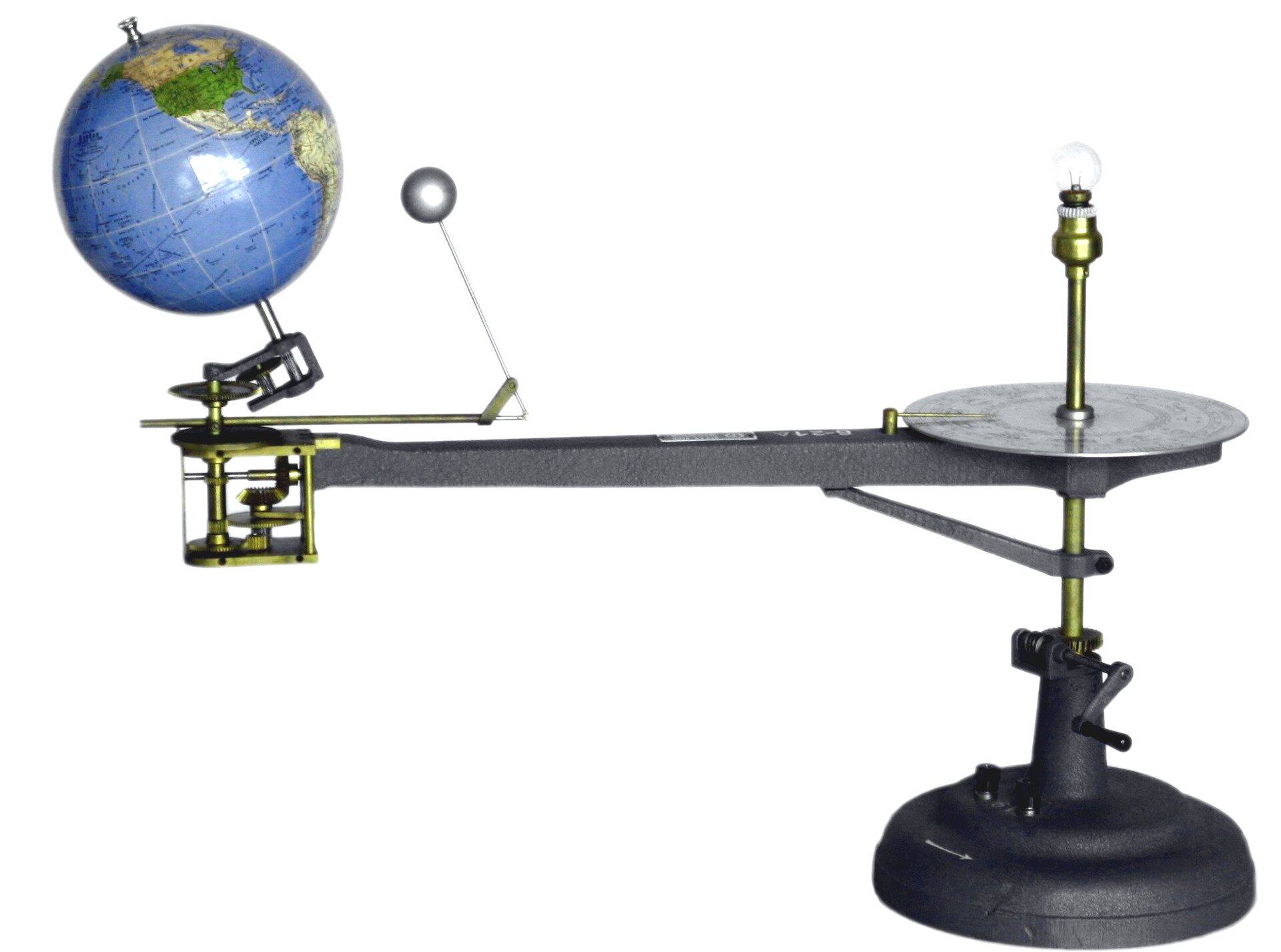 Zdjęcie przedstawia model do prezentacji ruchu Ziemi i Księżyca względem siebie oraz względem Słońca. Główna część modelu to podstawka po prawej stronie zdjęcia. Na pionowej osi, przymocowanej do podstawki, umocowano metalowe ramię w poziomie. Metalowe ramię skierowane w lewą stronę. Na końcu ramienia umieszczona kula ziemska. Kula ziemska nachylona w lewo. Na prawo od kuli ziemskiej mała srebrna kula. To Księżyc. Zarówno kula ziemska, jak i Księżyc mogą się swobodnie obracać wokół własnej osi oraz wokół Słońca. Księżyc dodatkowo może krążyć wokół Ziemi.  Tellurium is a model that allows the presentation of the mutual movement of the Earth and the Moon relative to each other and to the Sun. It is used to show the illumination of the Earth at various times both day and year, phases of the Moon and solar and lunar eclipses.