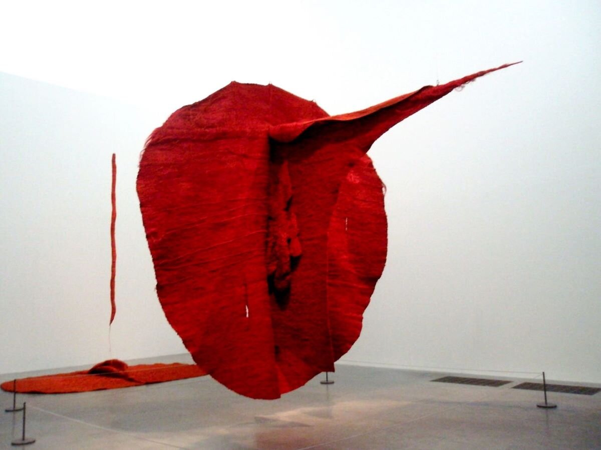 Ilustracja przedstawia dzieło Magdaleny Abakanowicz pt. „Abakan czerwony”. Abakan - to rodzaj tkaniny artystycznej będącej monumentalną kompozycją przestrzenną. „Abakan czerwony” jest formą przestrzenną w kształcie owalu, w jego części środkowej znajduje się wiele elementów o nieokreślonej formie. W górnej części owalu, pod kątem prostym znajduje się długi, zwężający się ostro zakończony element. Rzeźba jest monochromatyczna.
