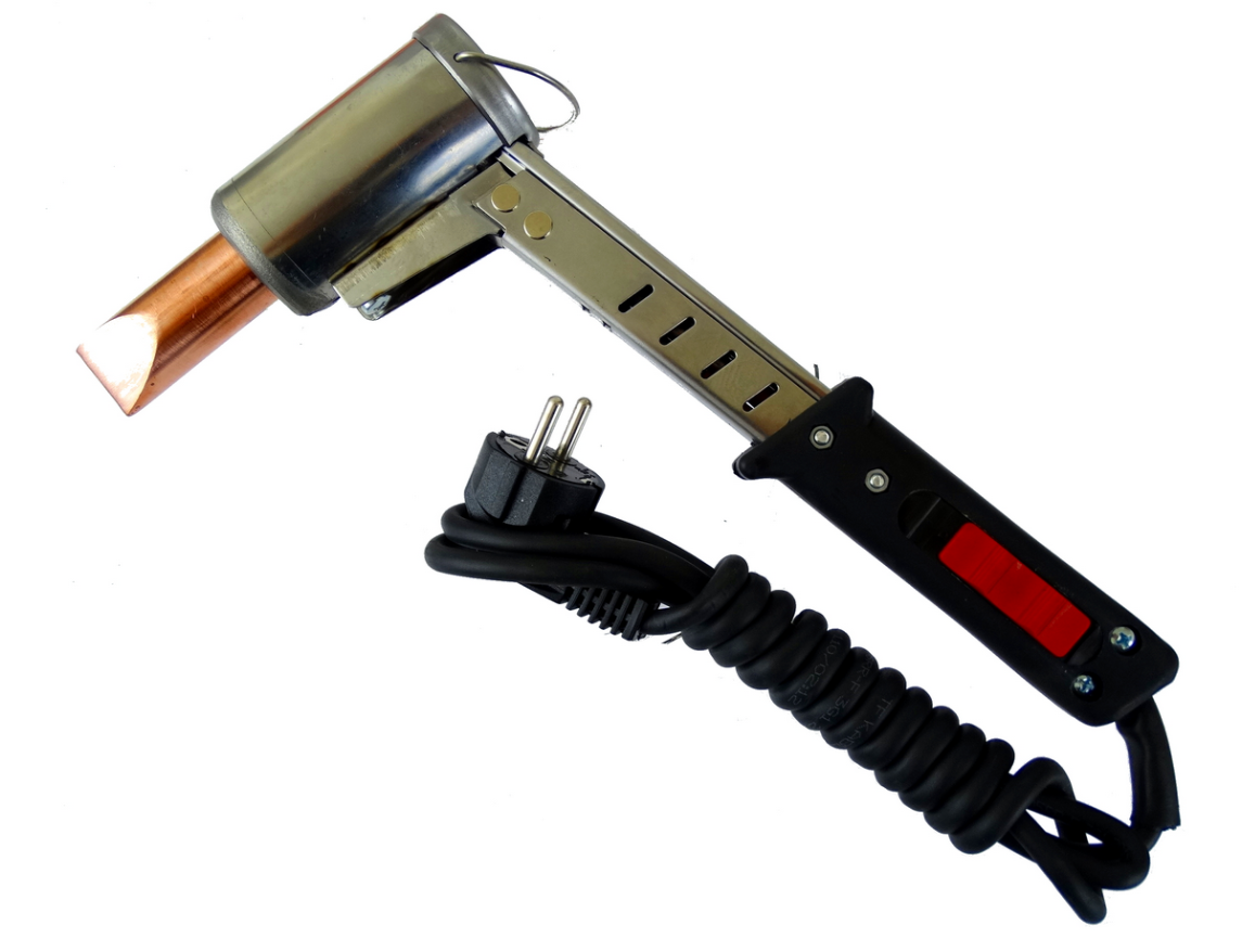 Grafika przedstawia lutownicę. Urządzenie to składa się z kolby lutowniczej (służącej jako uchwyt), elementu grzejnego i grotu, czyli elementu mającego bezpośredni styk ze spoiwem. Urządzenie jest podłączane do prądu za pomocą kabla zakończonego wtyczką.