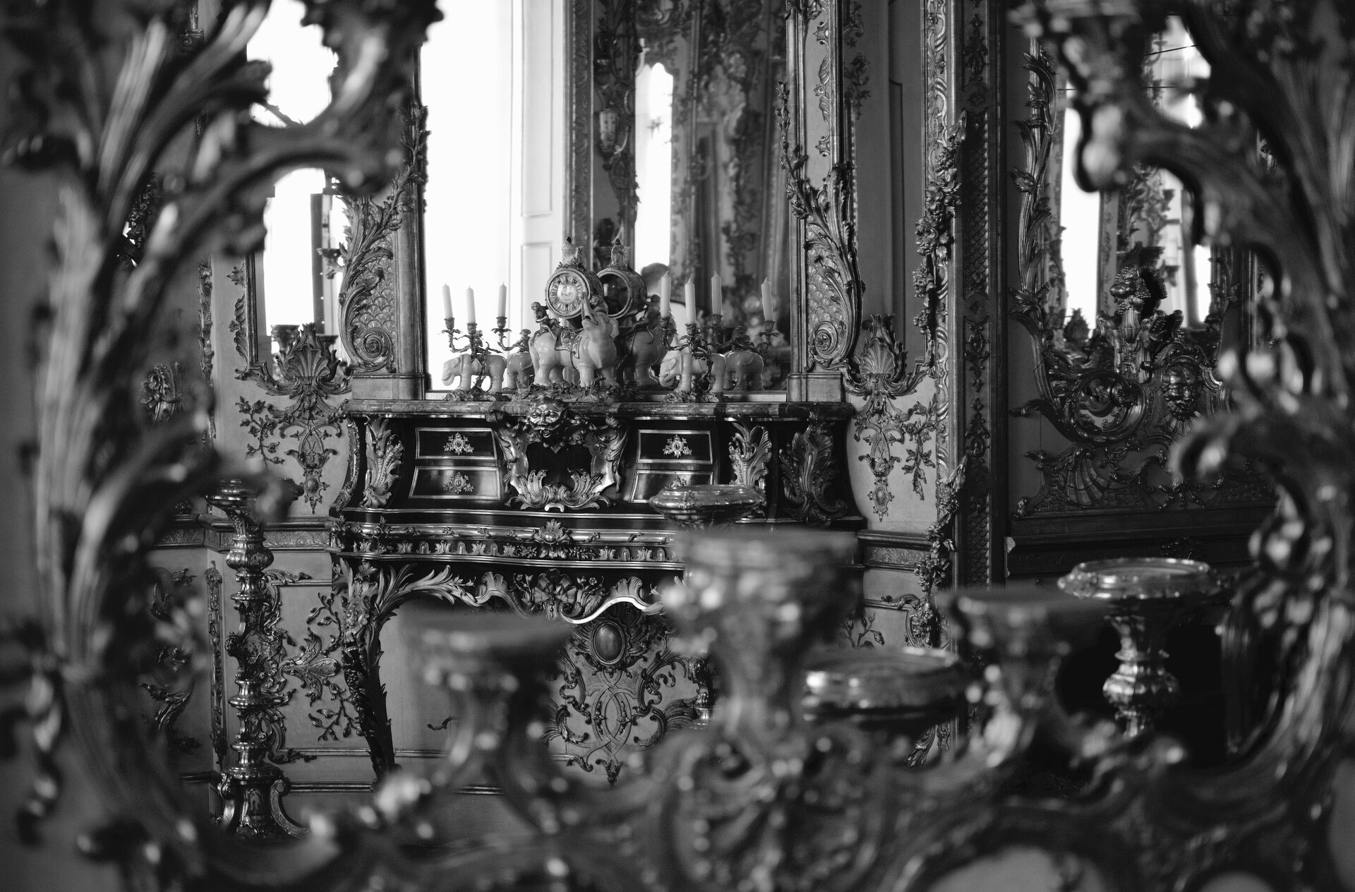Zdjęcie przedstawia wnętrze bogato zdobionej komnaty barokowej. Na ścianach widoczne sa liczne motywy kwiatowe. Znajdujące się meble są bogato rzeźbione, o zaokrąglonych kształtach.