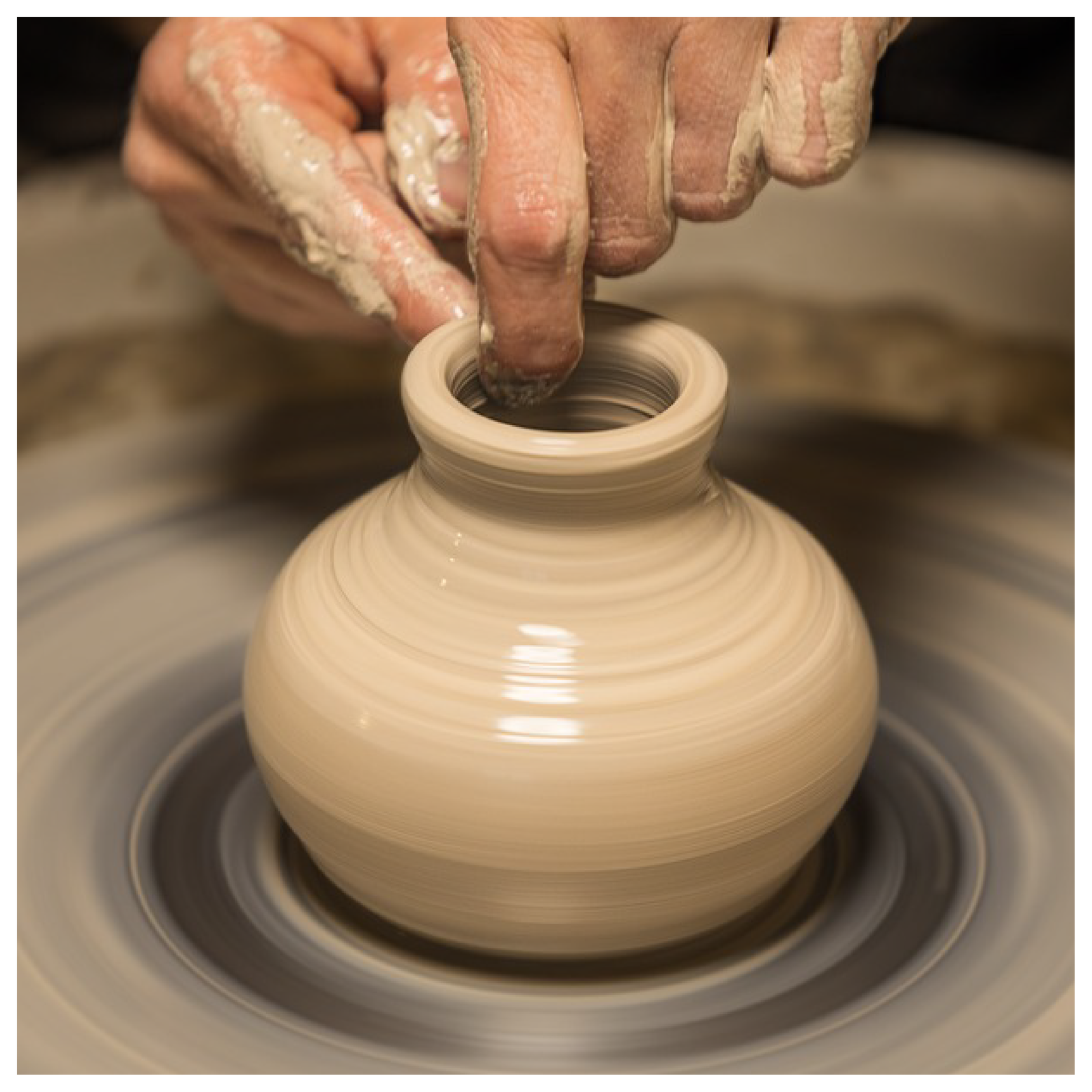 Zdjęcie przedstawia urządzenie do lepienia naczyń z gliny, na którym ktoś jest w trakcie tworzenia wazonika.