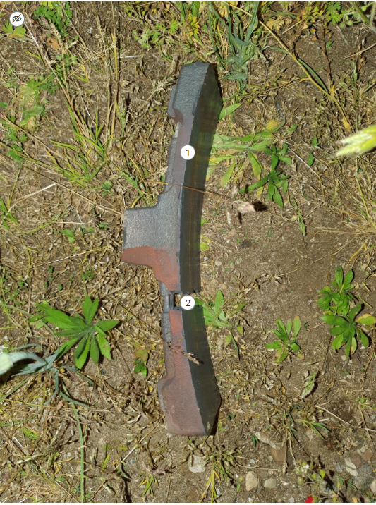 Na ilustracji przedstawiona jest uszkodzona wstawka hamulcowa. Jest to podłużny, lekko wygięty element żelazny, który pękł poprzecznie.