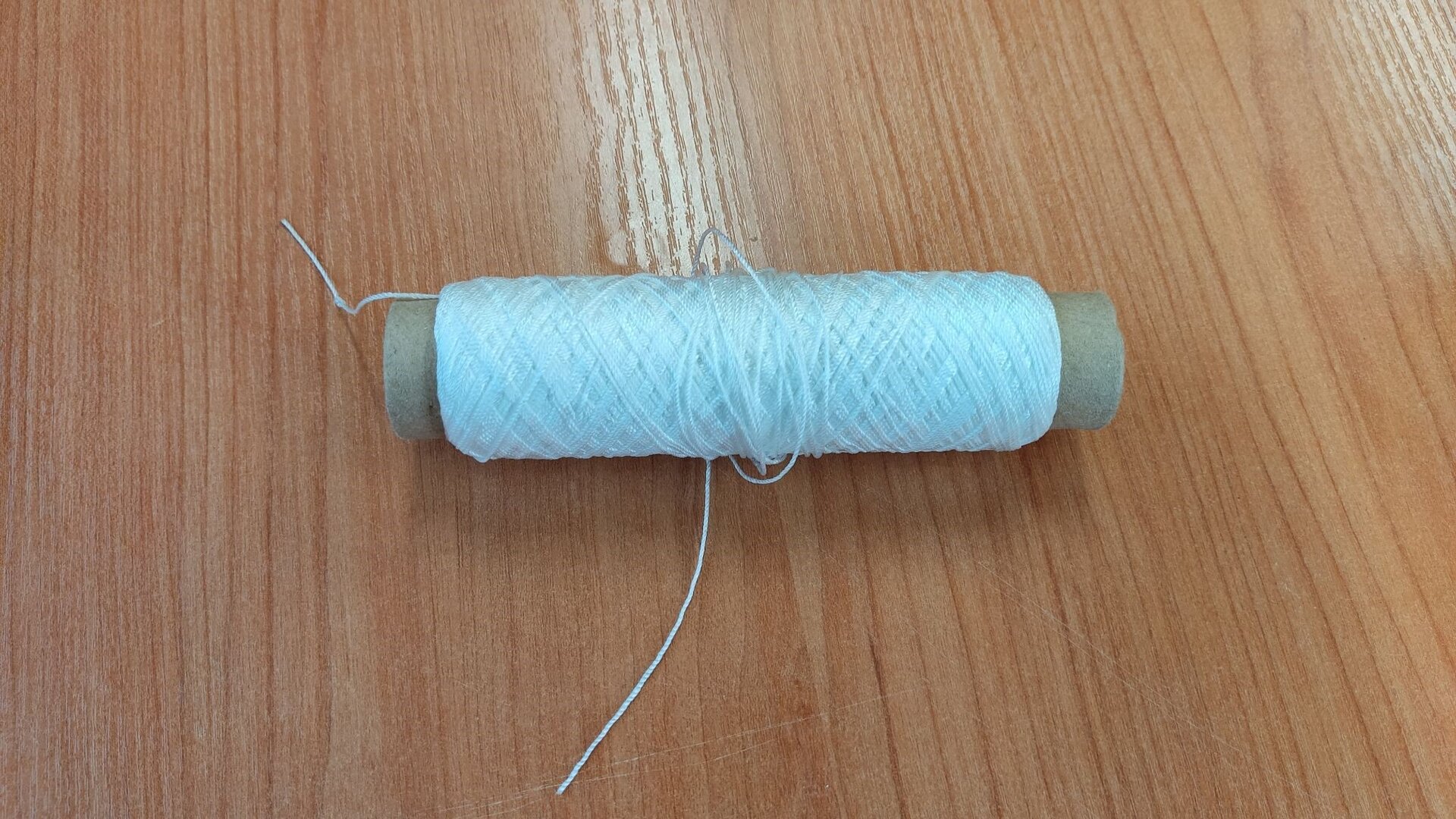 Zdjęcie przedstawia przędzę sieciową. Jest to nić nawinięta na szpulę.