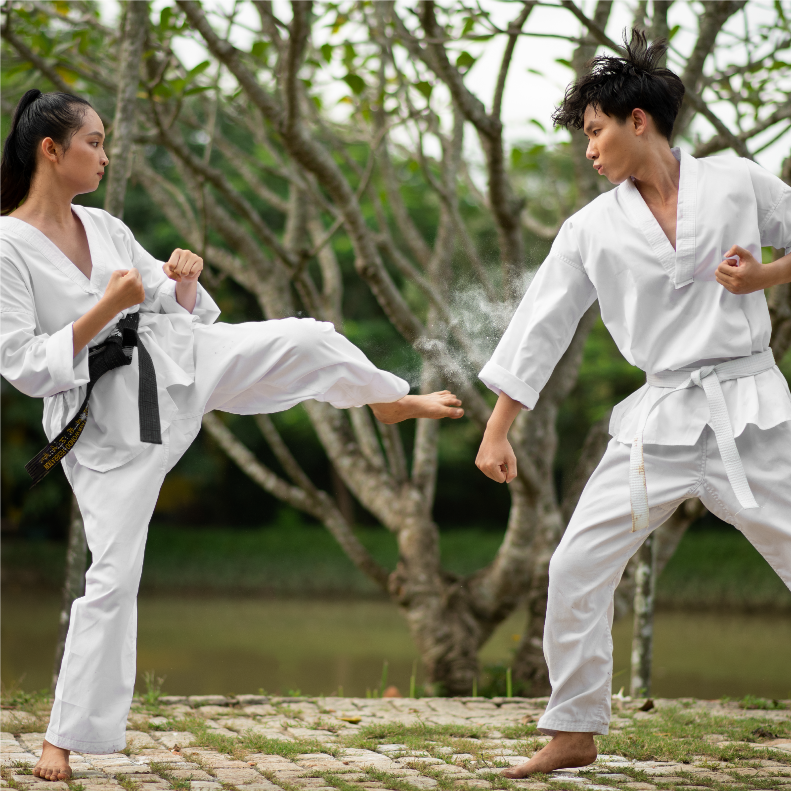 Zdjęcie przedstawia kobietę i mężczyznę w białych kimonach, ćwiczących sztuki walki. Ona ma czarny pas, a on biały.