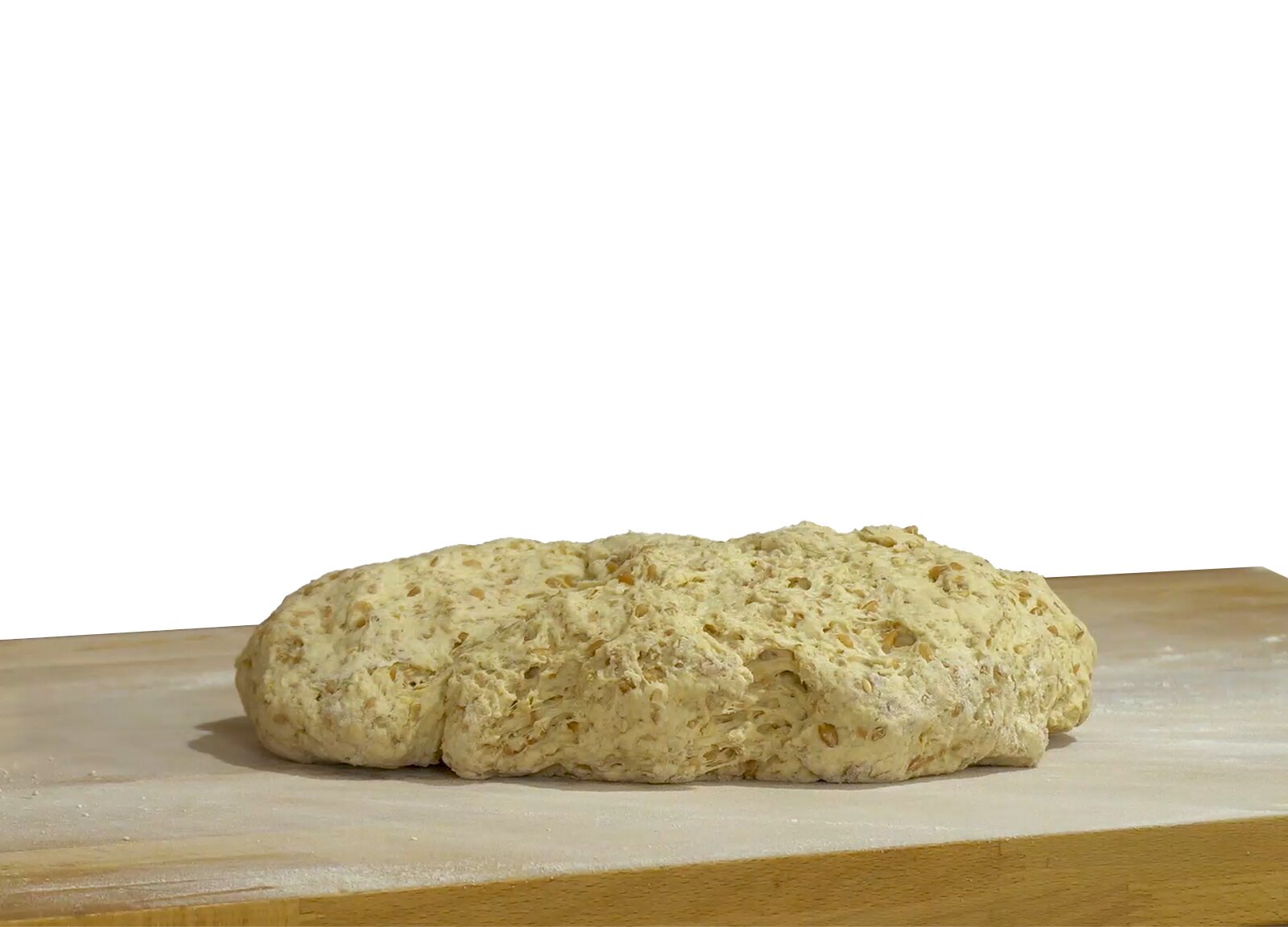 Zdjęcie przedstawia kęs pierwotny. Widoczny jest owalny, spłaszczony kęs ciasta w kolorze żółtym z brązowymi plamkami symbolizującymi ciasto żytnie. Kęs spoczywa na drewnianym prostokątnym blacie.