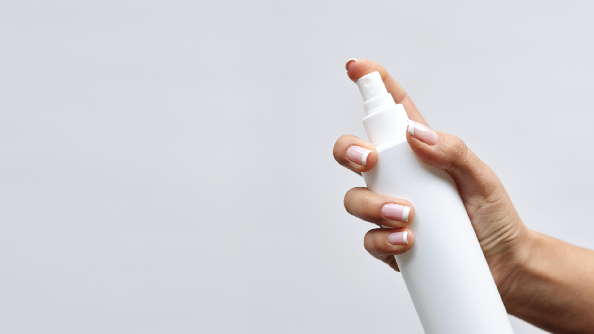 Zdjęcie przedstawia plastikowa butelkę z atomizerem trzymaną w dłoni osoby.