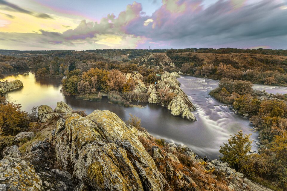 Zdjęcie obrazuje postrzeganie barw przez osobę chorą na deuteranopię – odmianę daltonizmu. Nie widzi ona barwy zielonej i myli ją z barwą czerwoną, pomarańczową lub żółtą. Zdjęcie, takie samo jak w poprzednim przykładzie przedstawia rzekę oraz otaczające ją tereny zielone – tereny zielone przedstawione są w odcieniach żółtego.  Pozostałe barwy nie zmieniły się