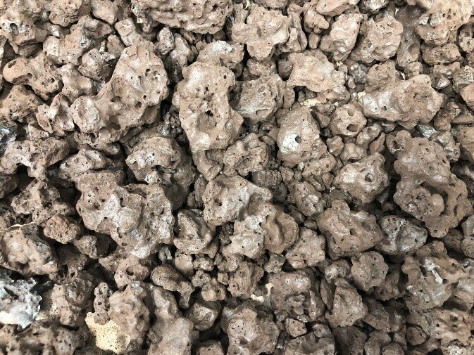 Na zdjęciu widać ziemiste grudki o nieregularnych kształtach. Grudki mają widoczne otwory. Grudki tworzą zbitą masę.