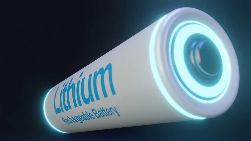 Na ilustracji znajduje się bateria litowo‑jonowa z napisem Lithium Rechargeable Battery, przedstawiona w dużym zbliżeniu na ciemnym tle, z podświetlonymi krawędziami.