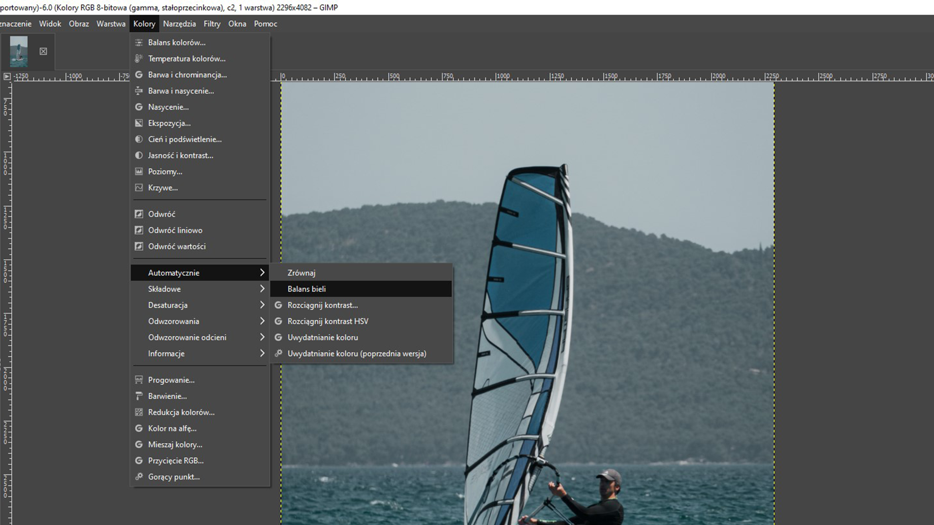Ilustracja przedstawia okno programu. Z menu wybrano zakładkę Kolory. Z listy wybrano Automatycznie, a następnie Balans bieli. W obszarze roboczym jest zdjęcie mężczyzny na windsurfingu.  