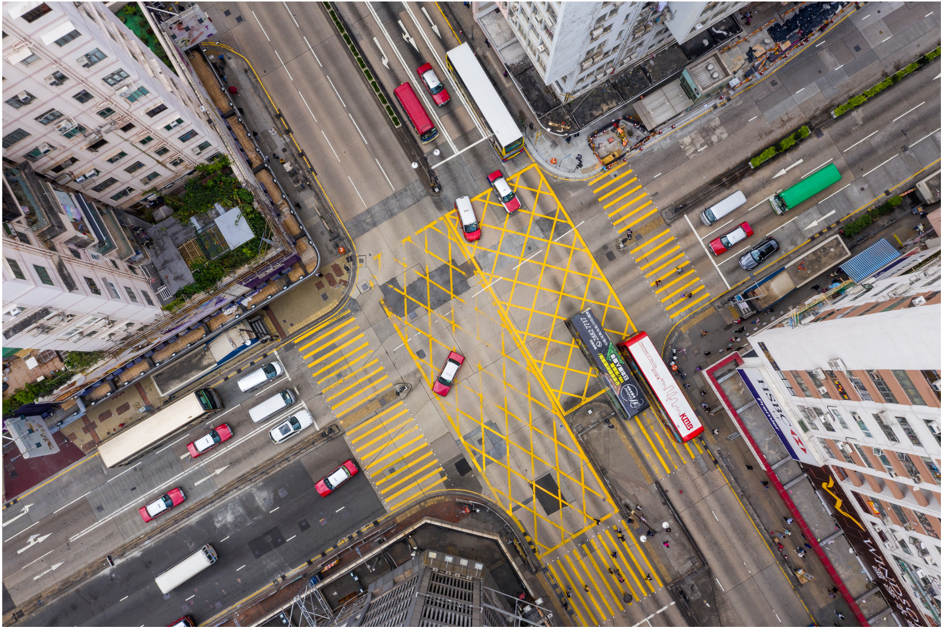 Zdjęcie przedstawia ruchliwe skrzyżowanie trzypasmowych ulic, sfotografowane z lotu ptaka na. Wokół znajdują się wieżowce. 