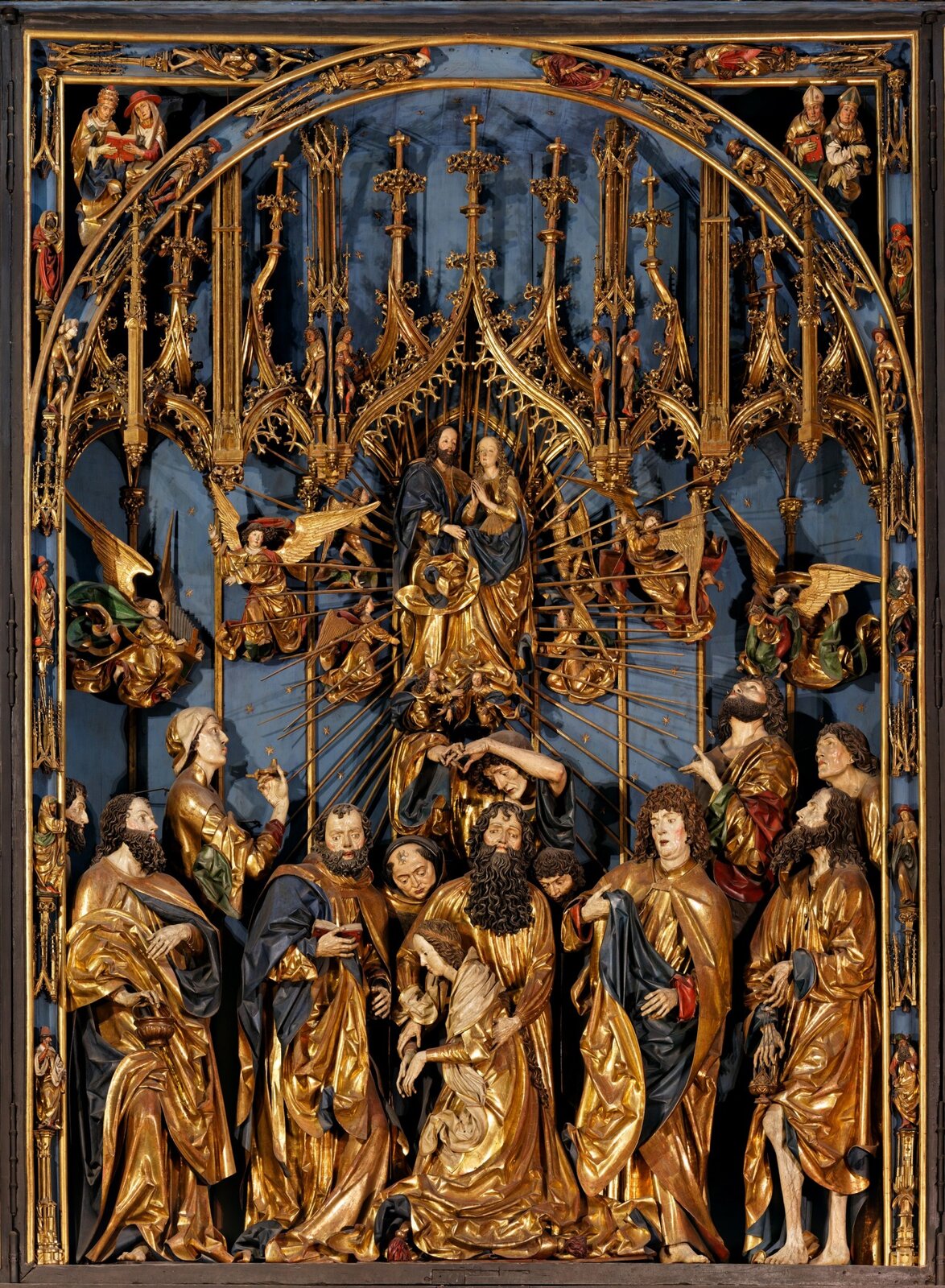 Ilustracja przedstawia scenę główną z Ołtarza Mariackiego. Dominuje w niej kolor złoty oraz niebieski. Na tym fragmencie ołtarzu widoczne są figury osób. W centrum znajduje się mężczyzna i kobieta.